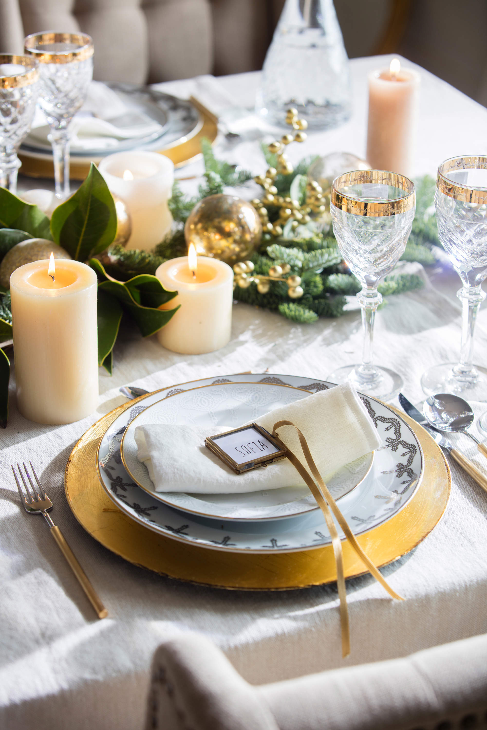 Mesa de Navidad en blanco y oro, decorada con velas y elementos vegetales.