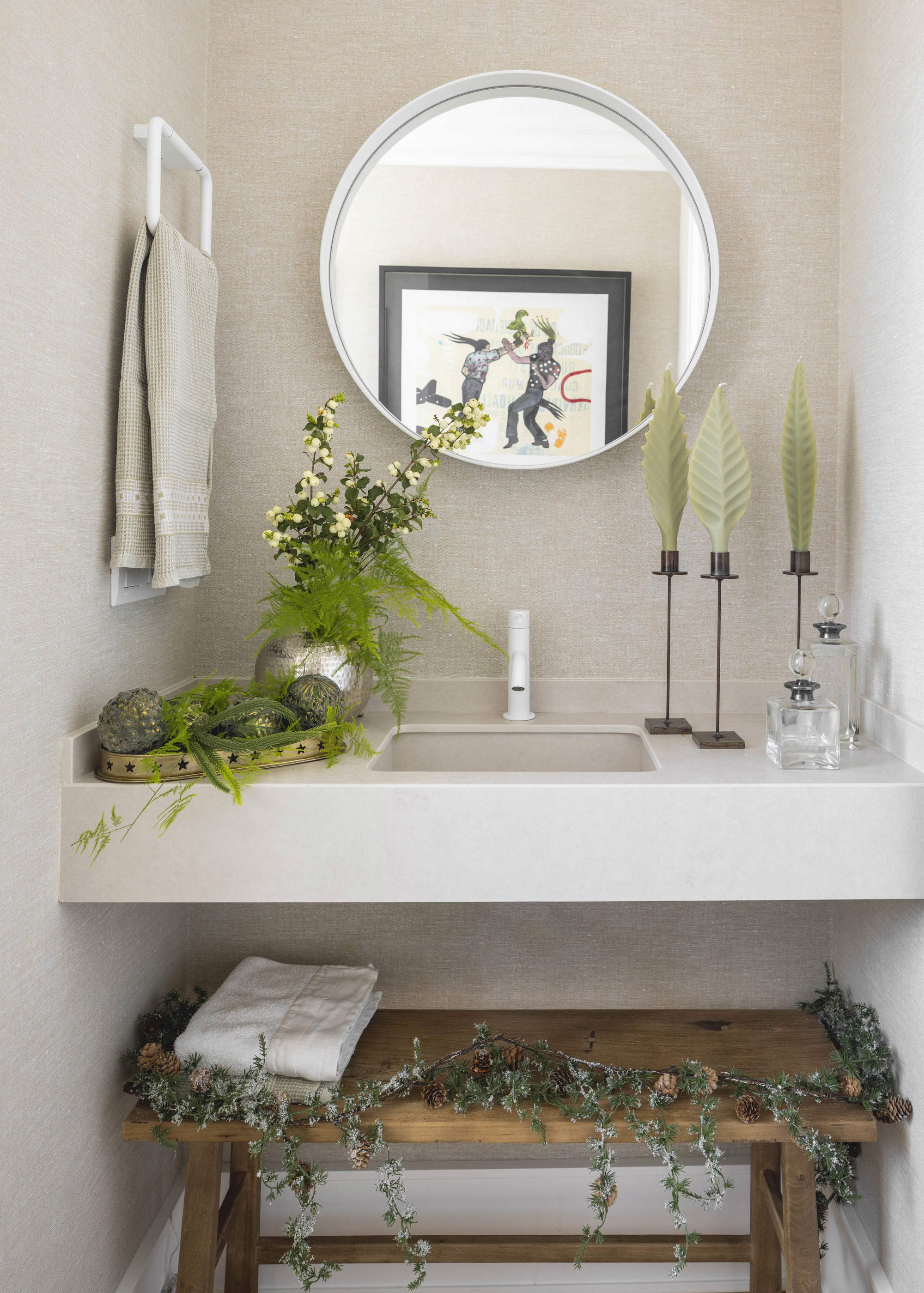 Baño decorado con elementos vegetales de estilo natural, banqueta de madera, espejo redondo.
