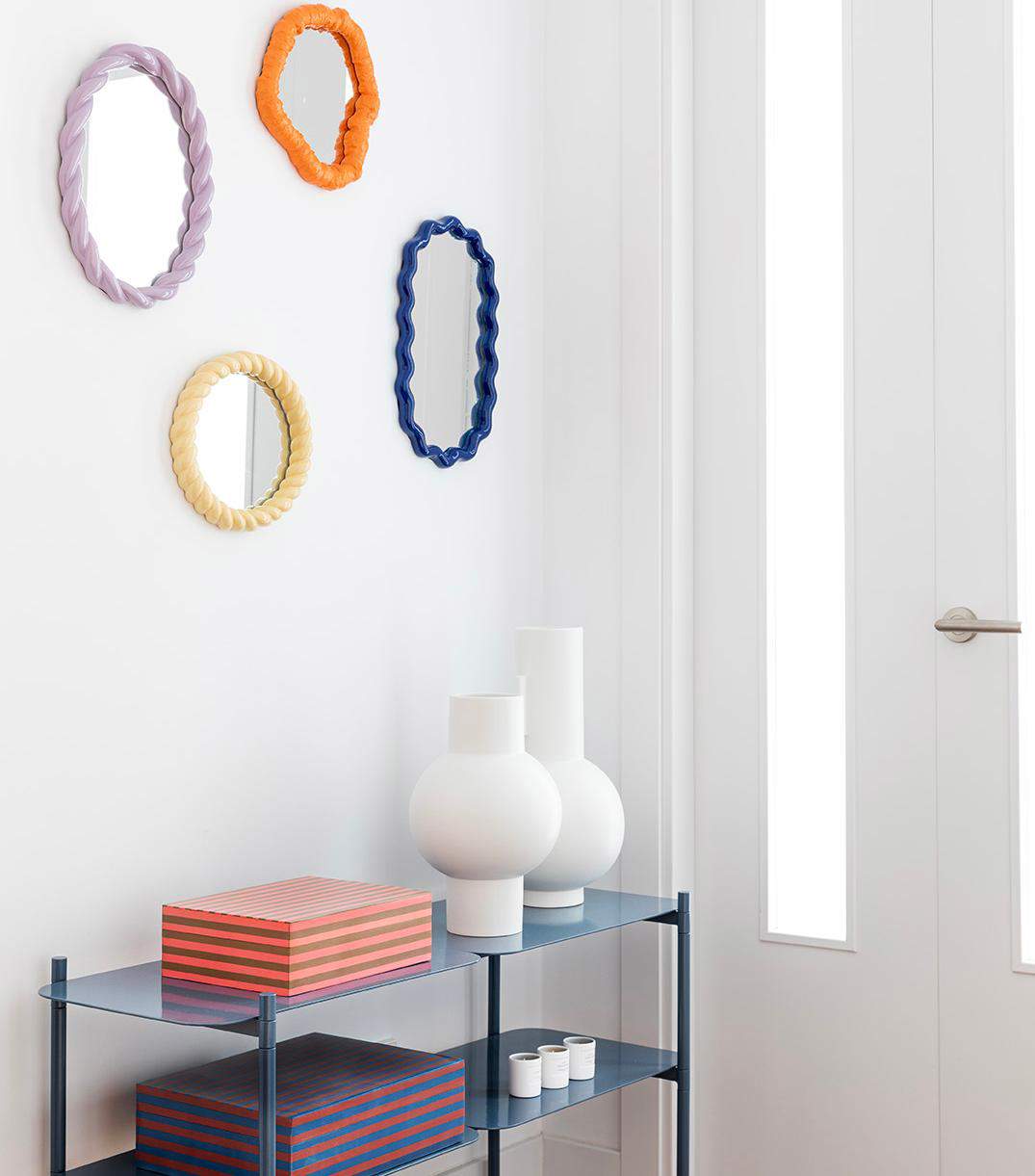 Recibidor decorado con una composición de espejos de formas y colores diferentes.