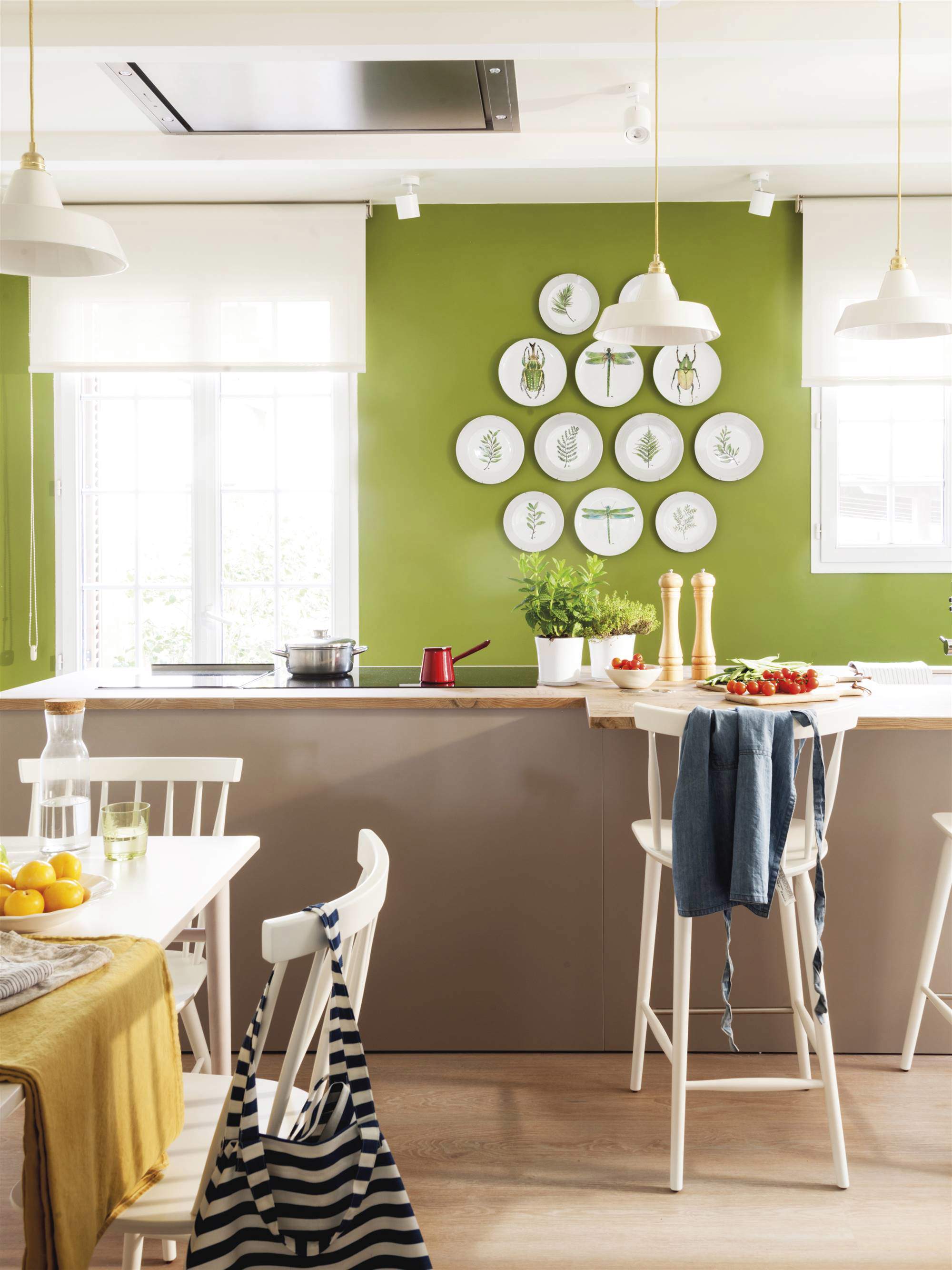 Cocina pintada en verde con isla y platos decorando la pared