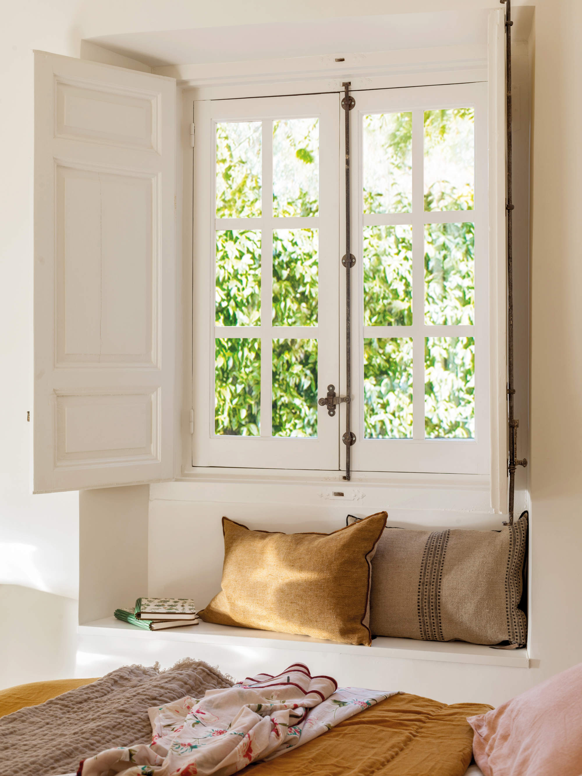 banco bajo la ventana en dormitorio pequeño.