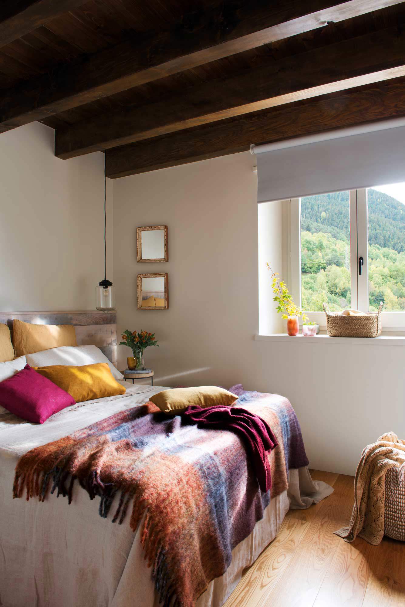 Dormitorio con techo de vigas de madera y manta multicolor