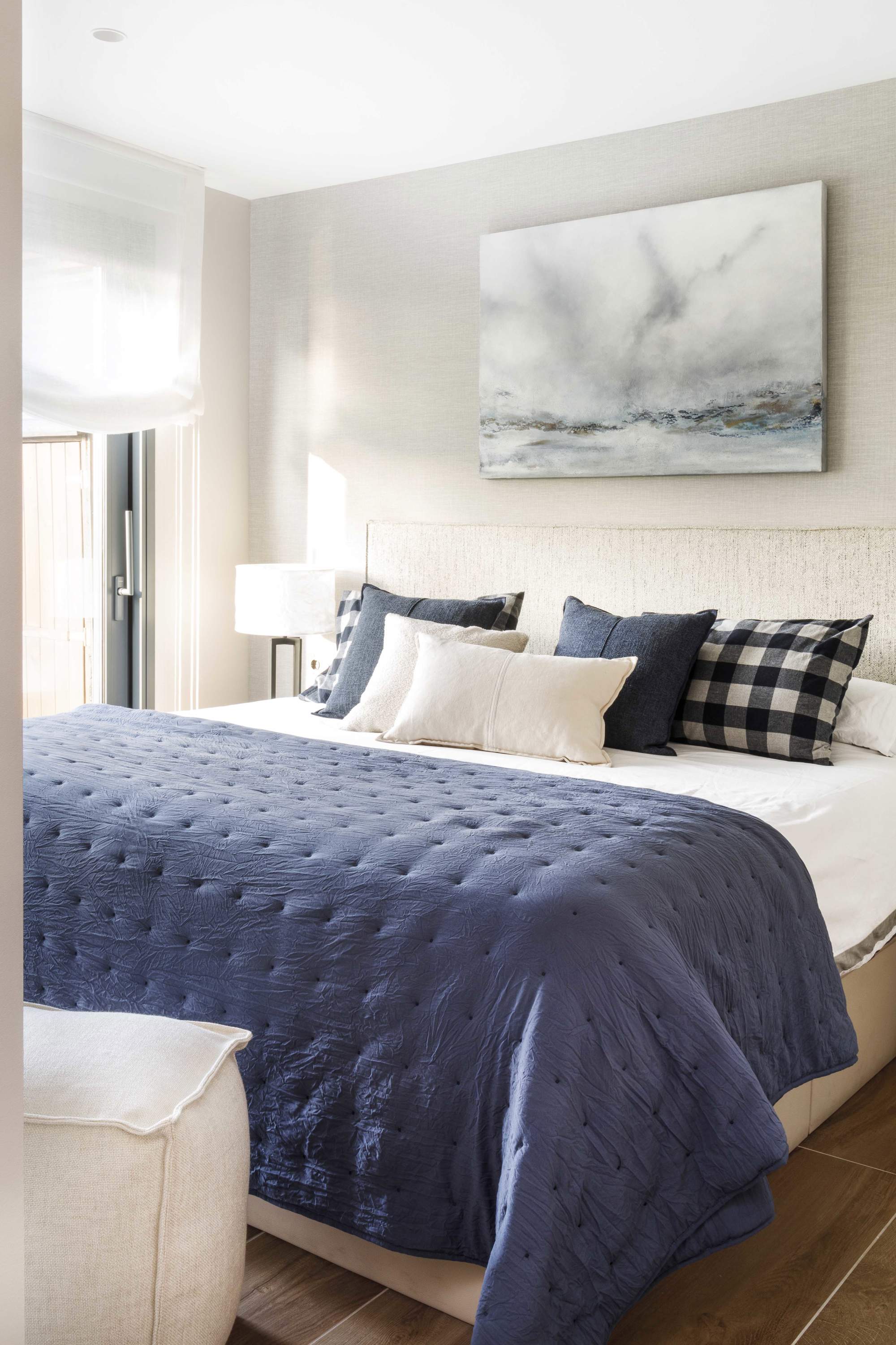 Dormitorio principal con cabecero tapizado y textiles azul marino