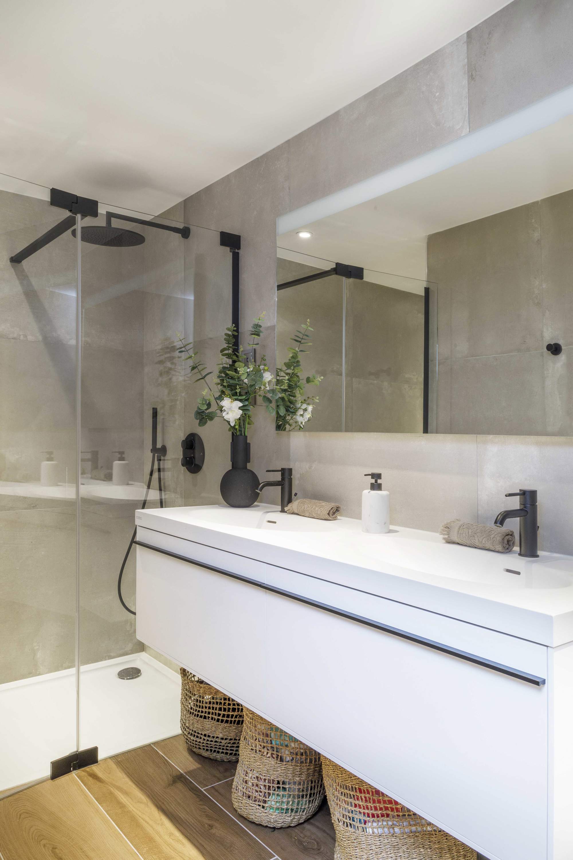 Baño con lavamanos volado y duchas con acabados en negro metalizado