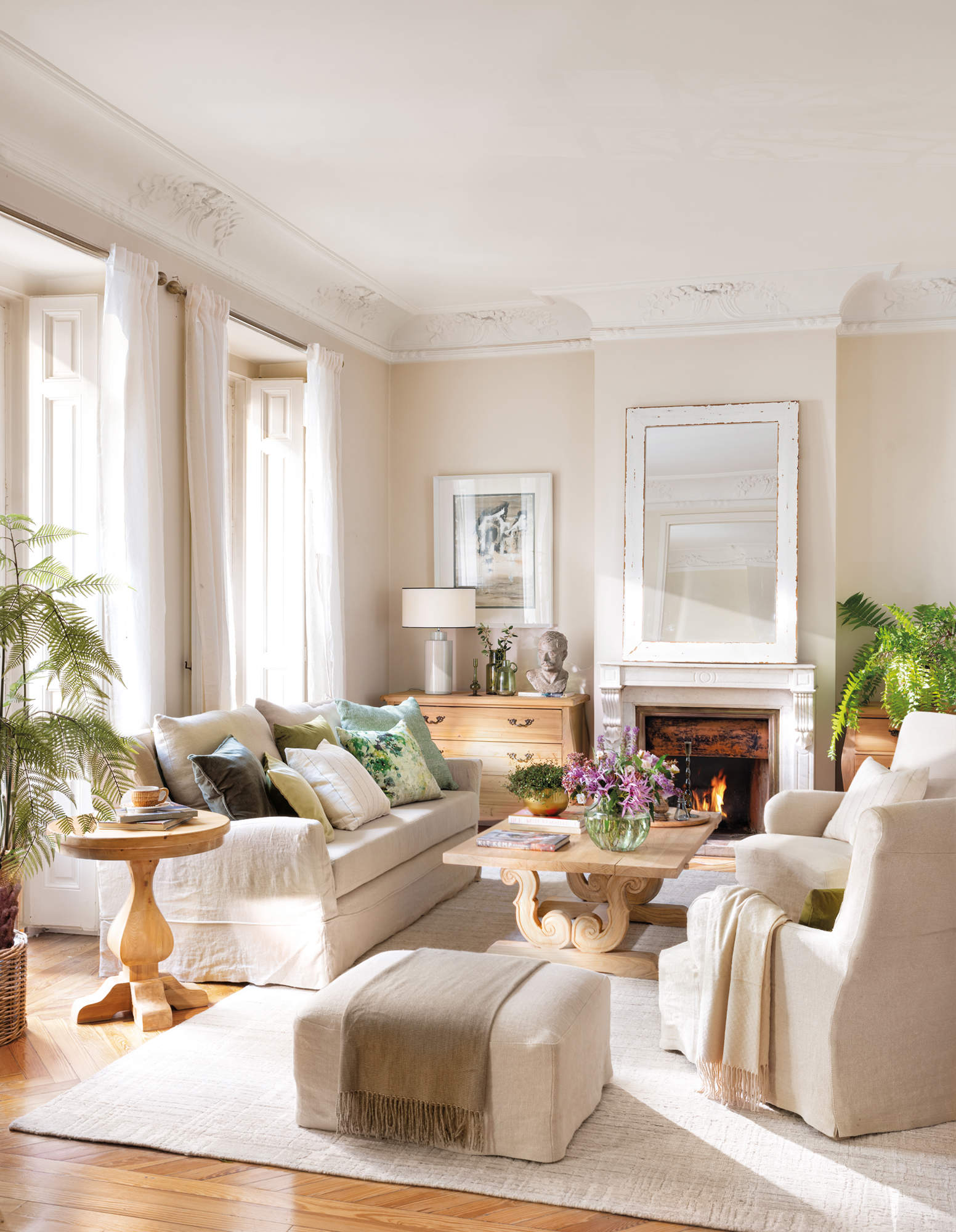 Salón neoclásico con molduras, muebles de madera, sofás de lino y chimenea.
