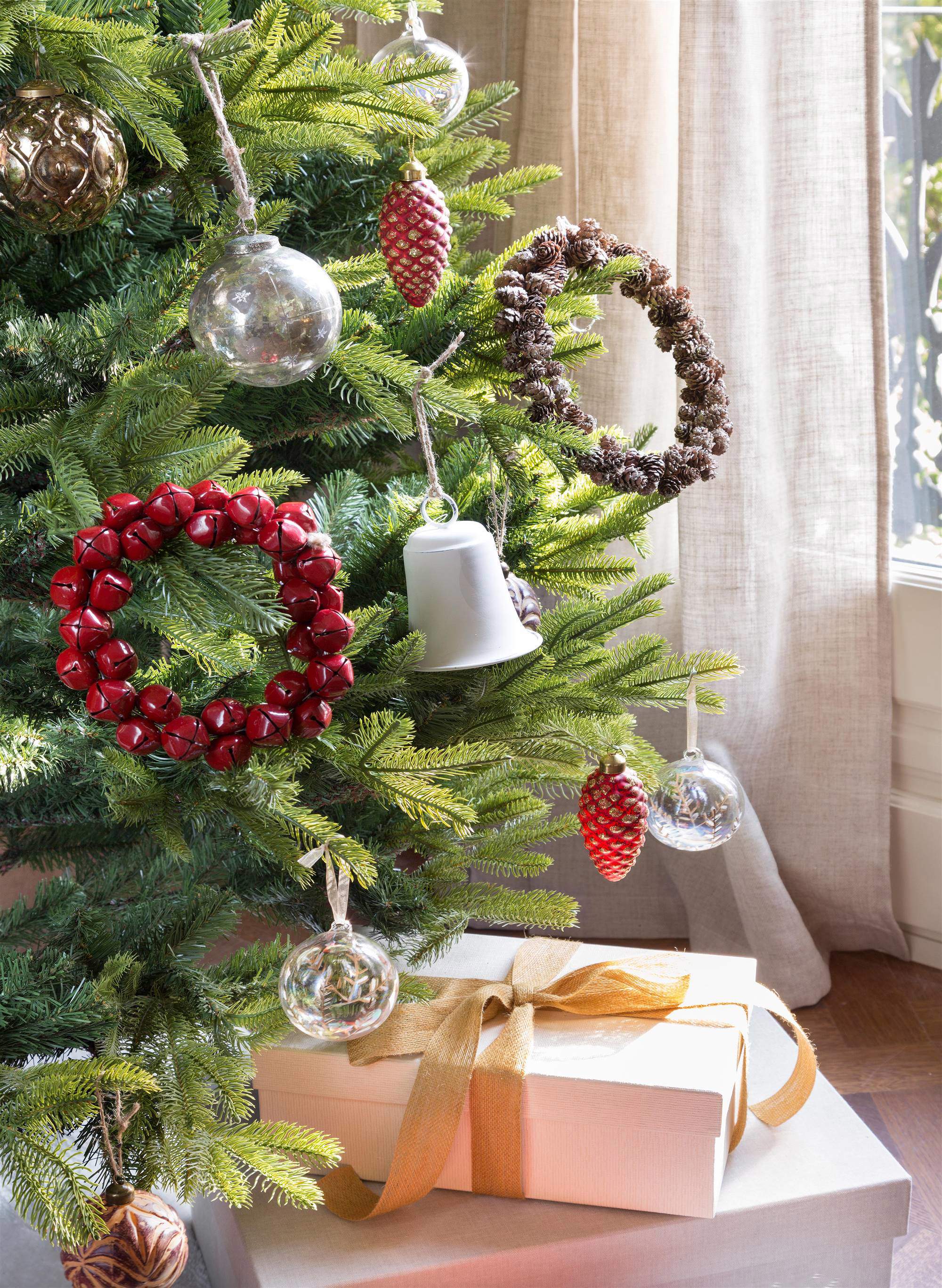 Árbol de Navidad decorado con coronas, campanas, piñas y bolas de cristal.