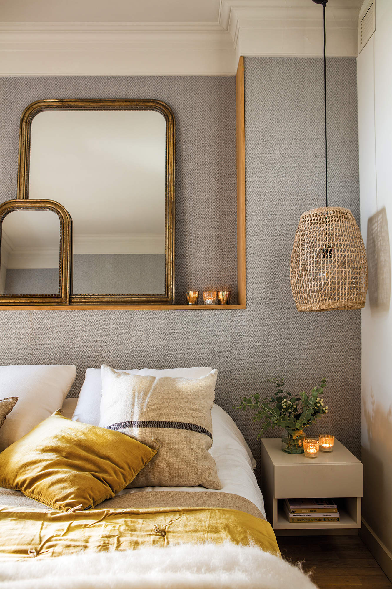 Detalles del dormitorio principal, textiles en lana y terciopelo mostaza y blanco, espejos de marco dorado y lámpara de techo de ratán.