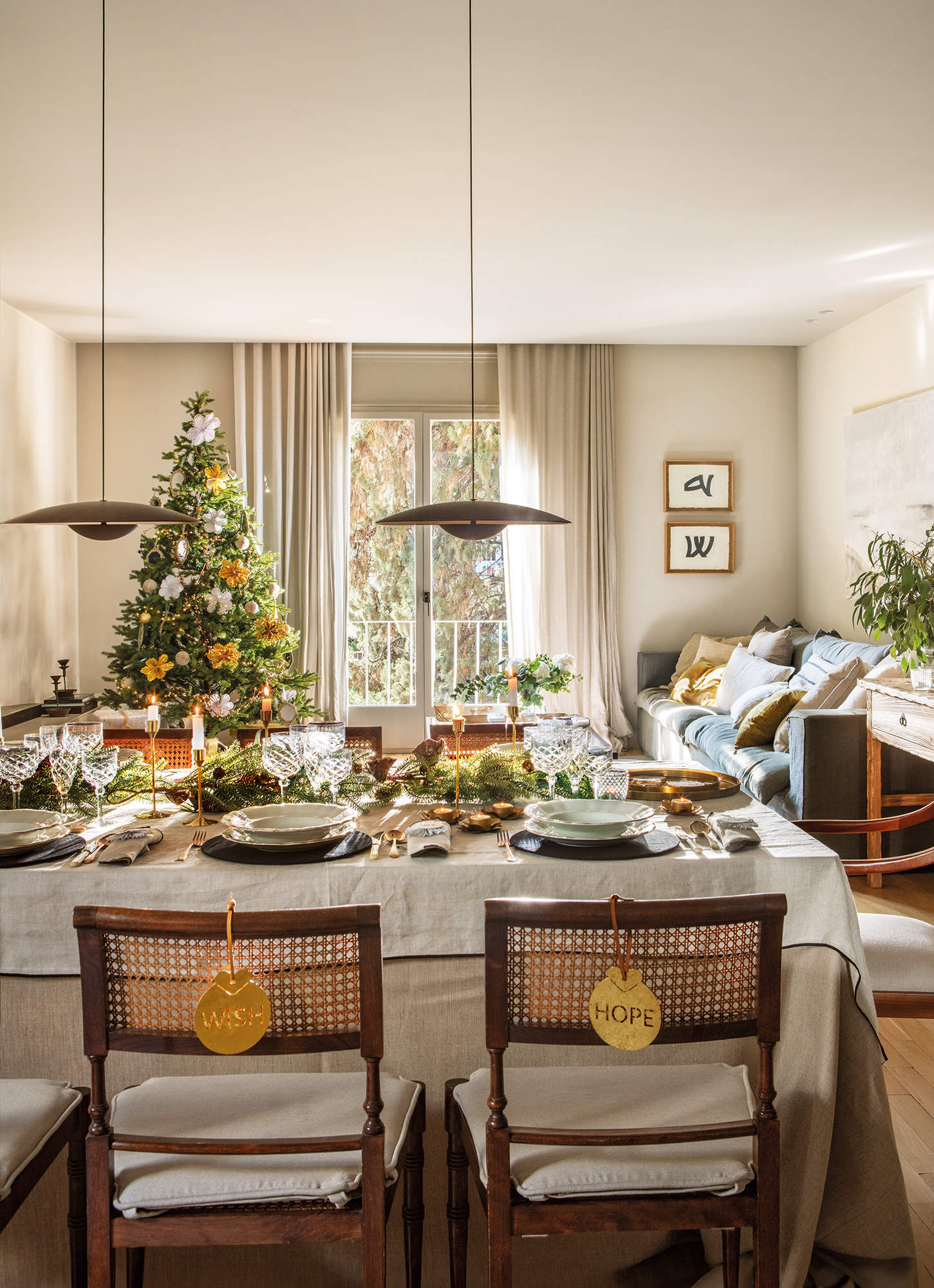 Salón comedor decorado de Navidad elegante y actual, adornos en dorado, muebles de madera y textiles cálidos.