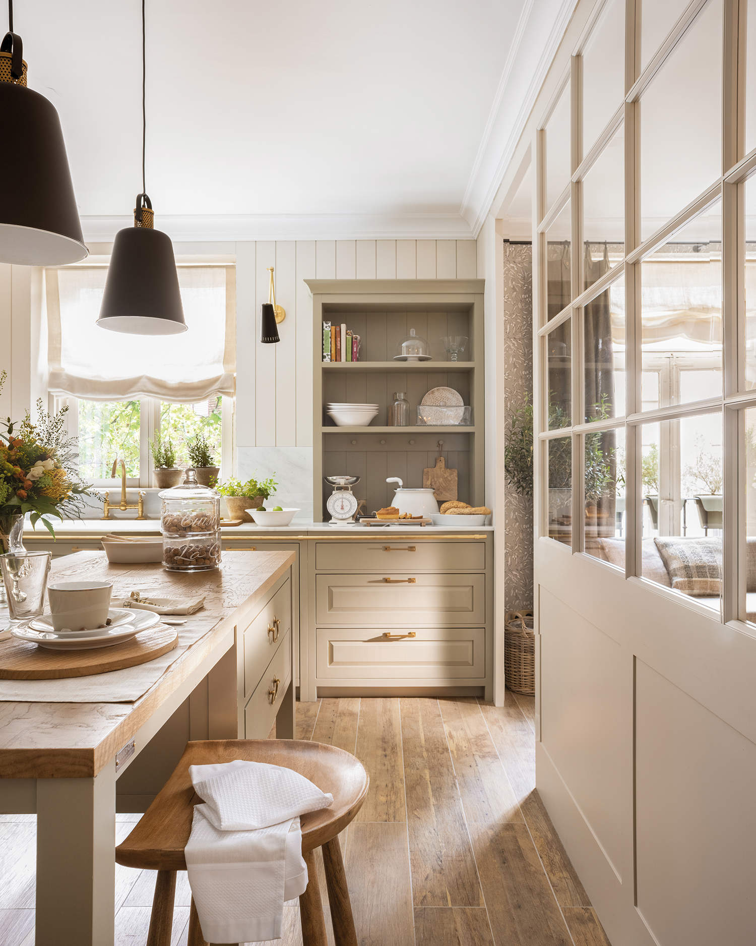 Cocina cálida con isla y muebles a medida con puerta de cristal