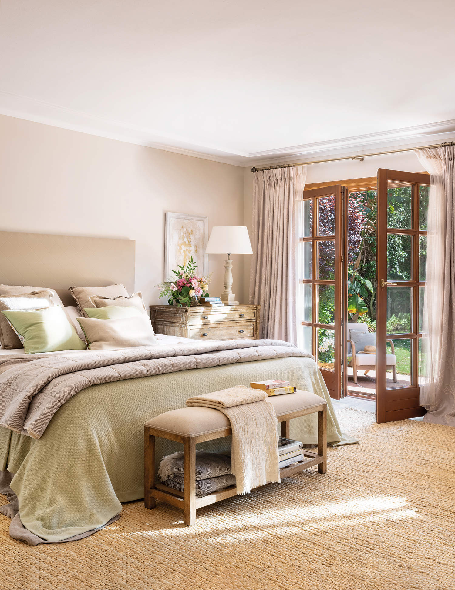 Dormitorio cálido con cabezal tapizado beige y salida a la terraza