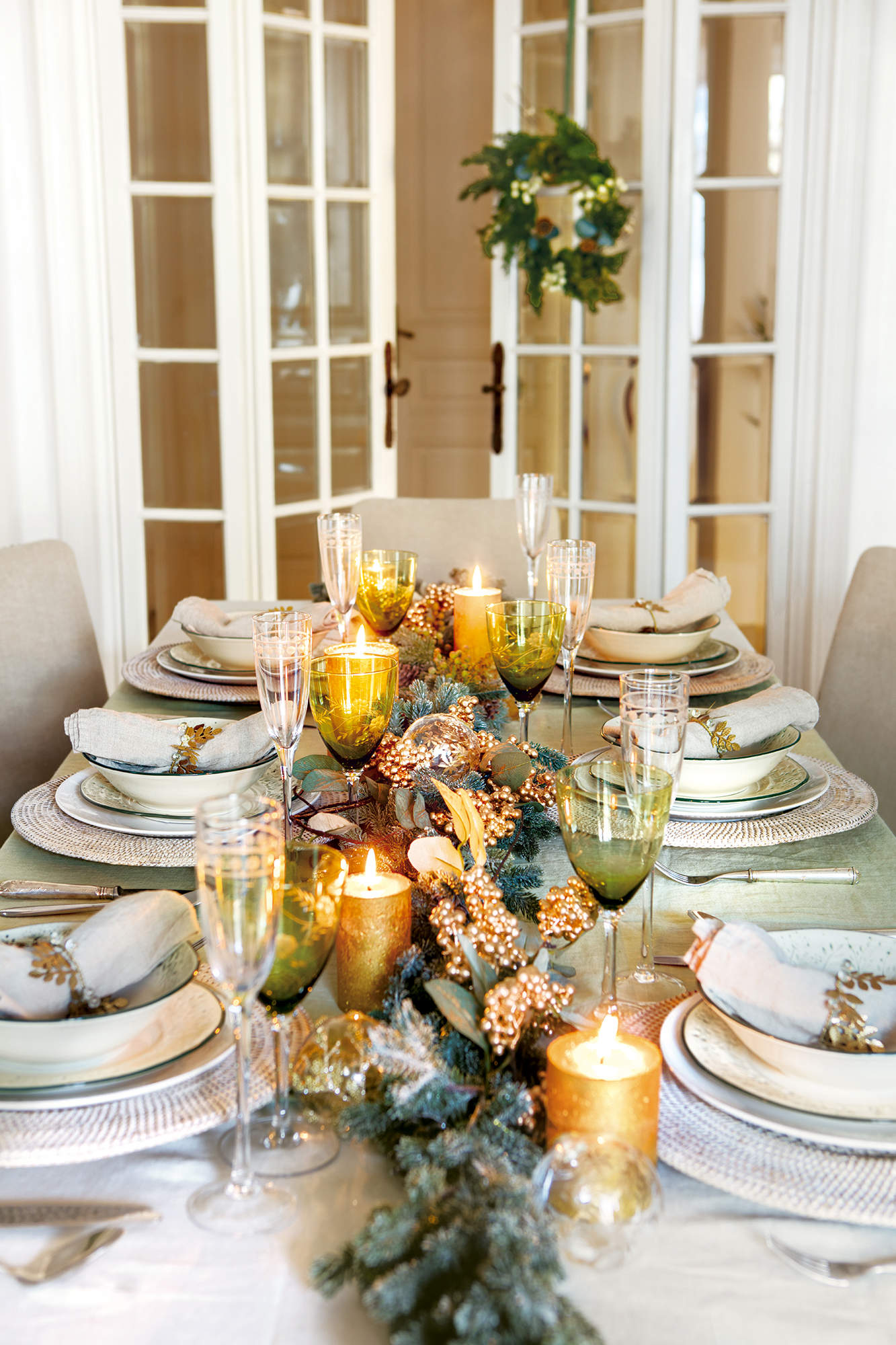 Centro de mesa con velas doradas y ramas naturales con hojas pintadas