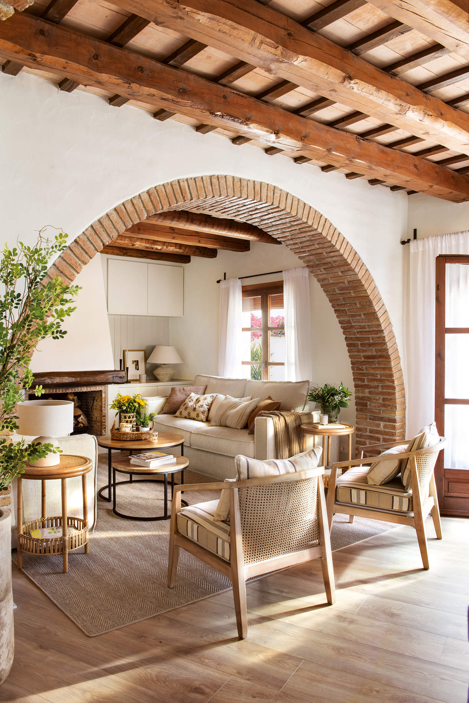 Salón cálido con sofá beige, butacas de madera y chimenea de obra