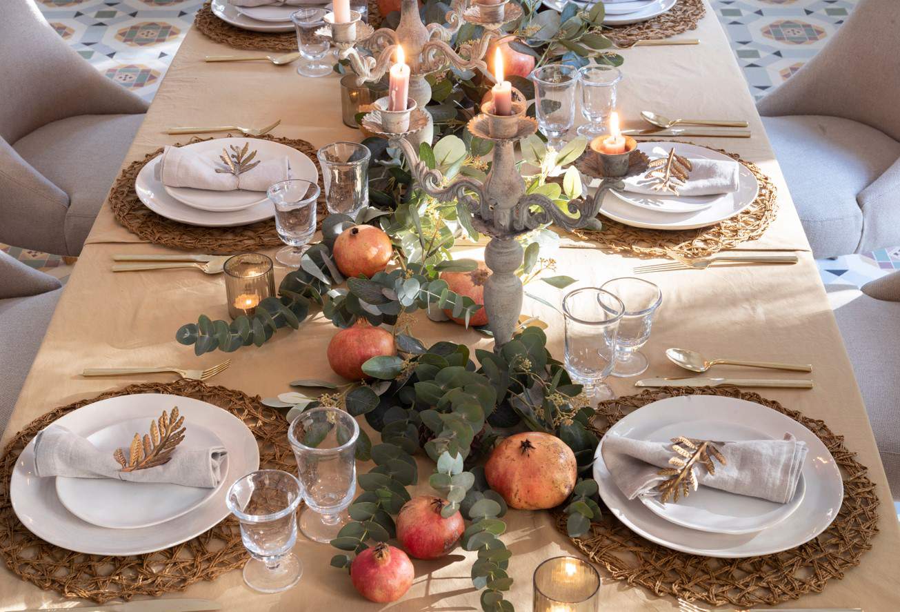 Centro de mesa con ramas naturales, frutas y candelabros en gris.