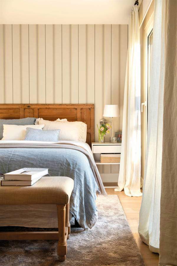 Dormitorio con pared del cabecero con papel a rayas verticales.
