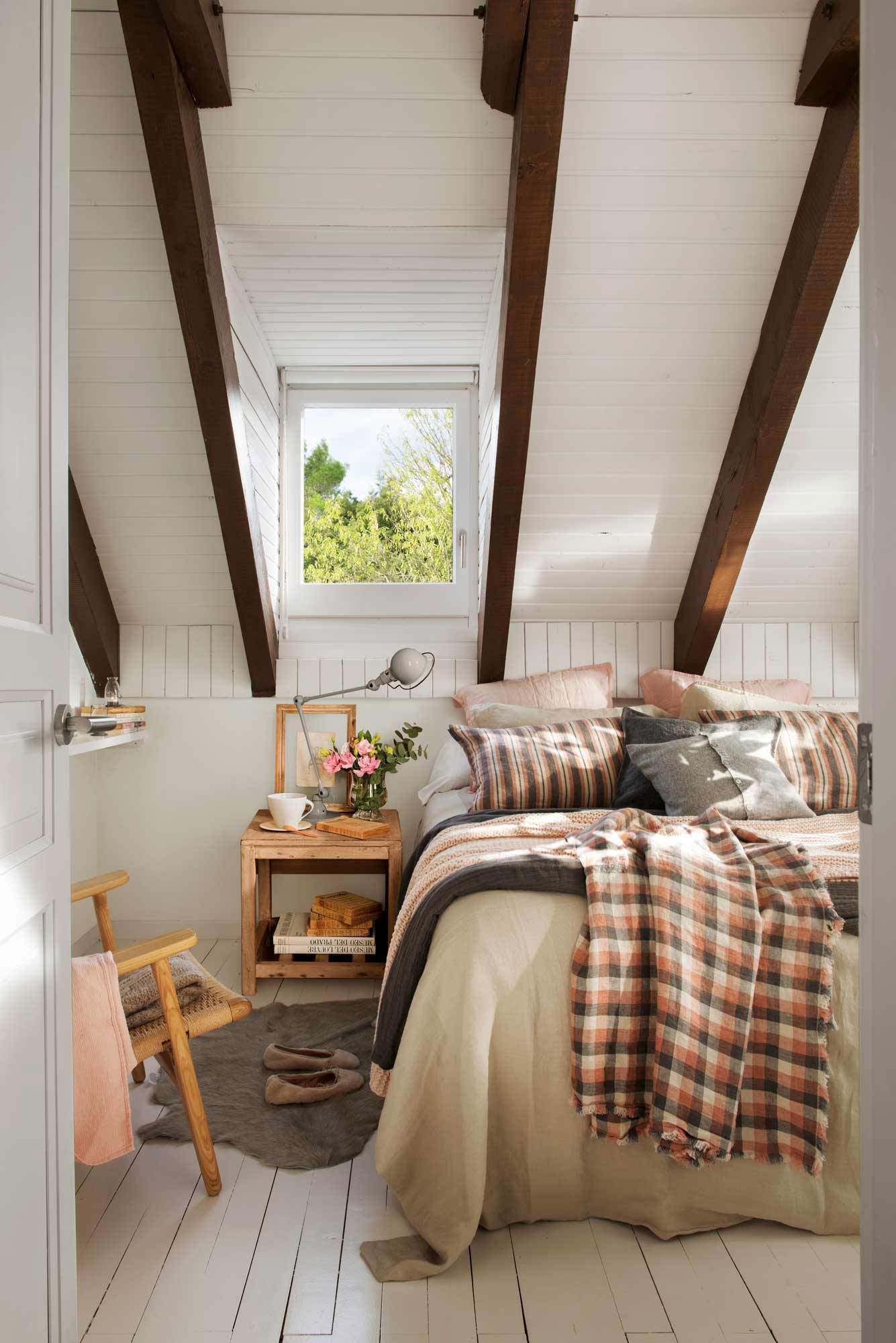 Dormitorio con techo abuhardillado, vigas a la vista y textiles en rosa