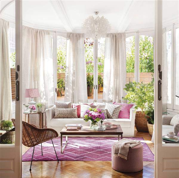Salón con sofá blanco y toques de color rosa.