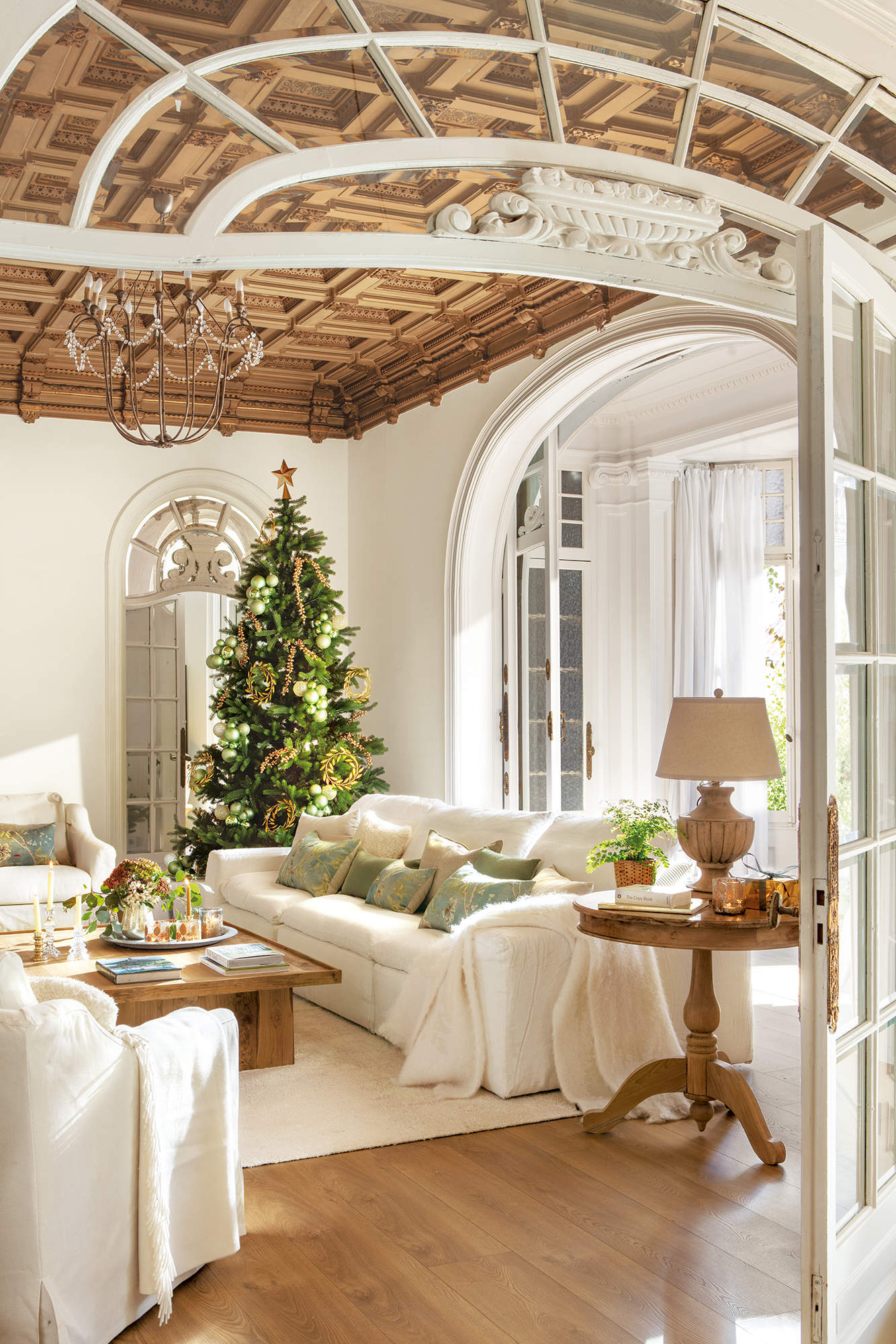 Salón elegante de Navidad con techo de molduras, puertas en arco y lámpara de araña.