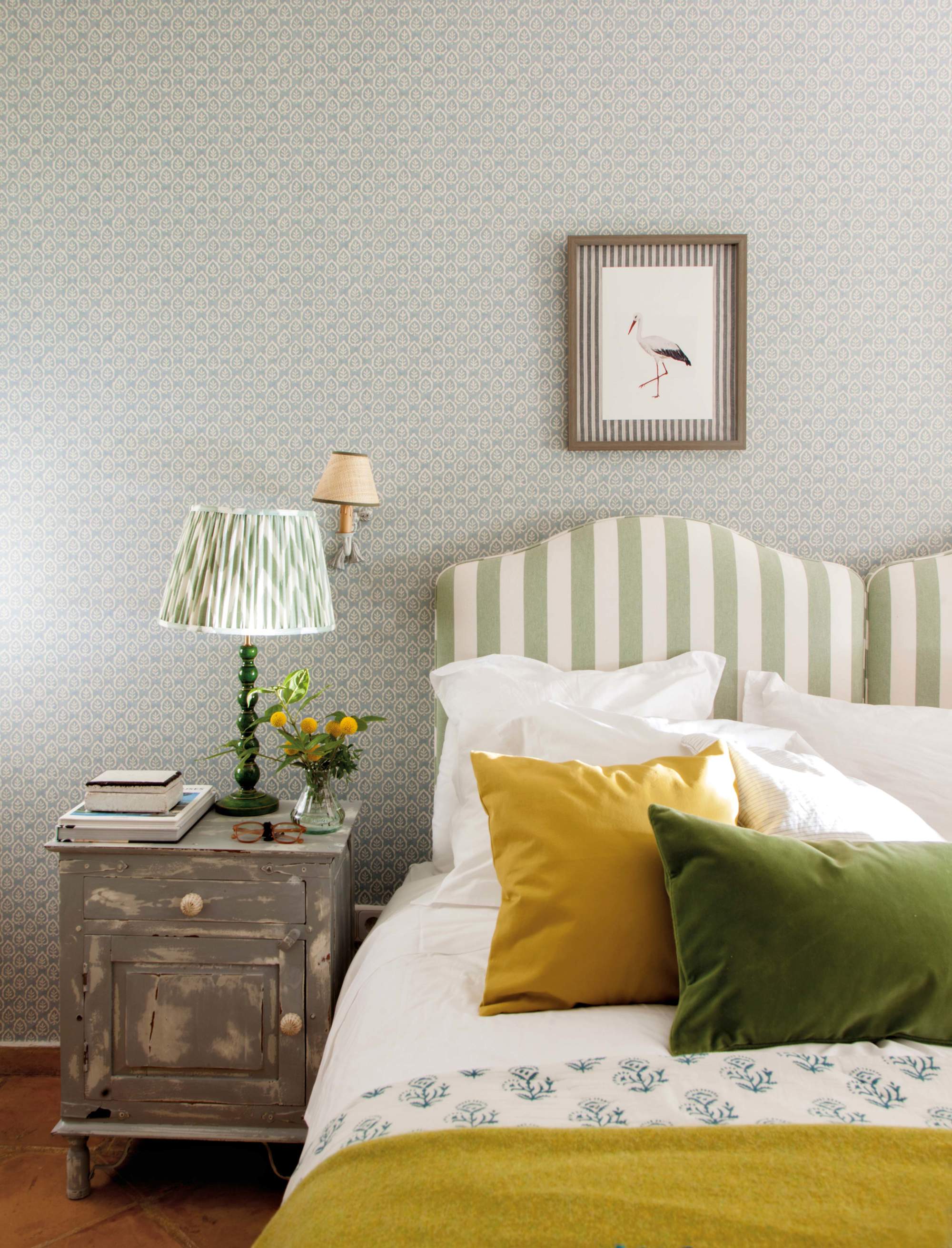 Dormitorio con cabecero a rayas verde y lámpara de sobremesa plisada