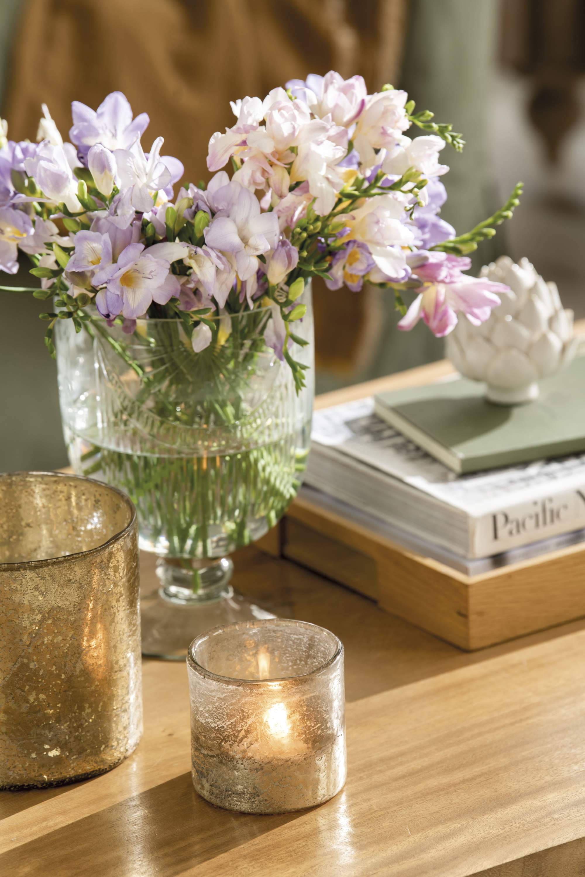 Mesa de centro con jarrón con flores y velas.