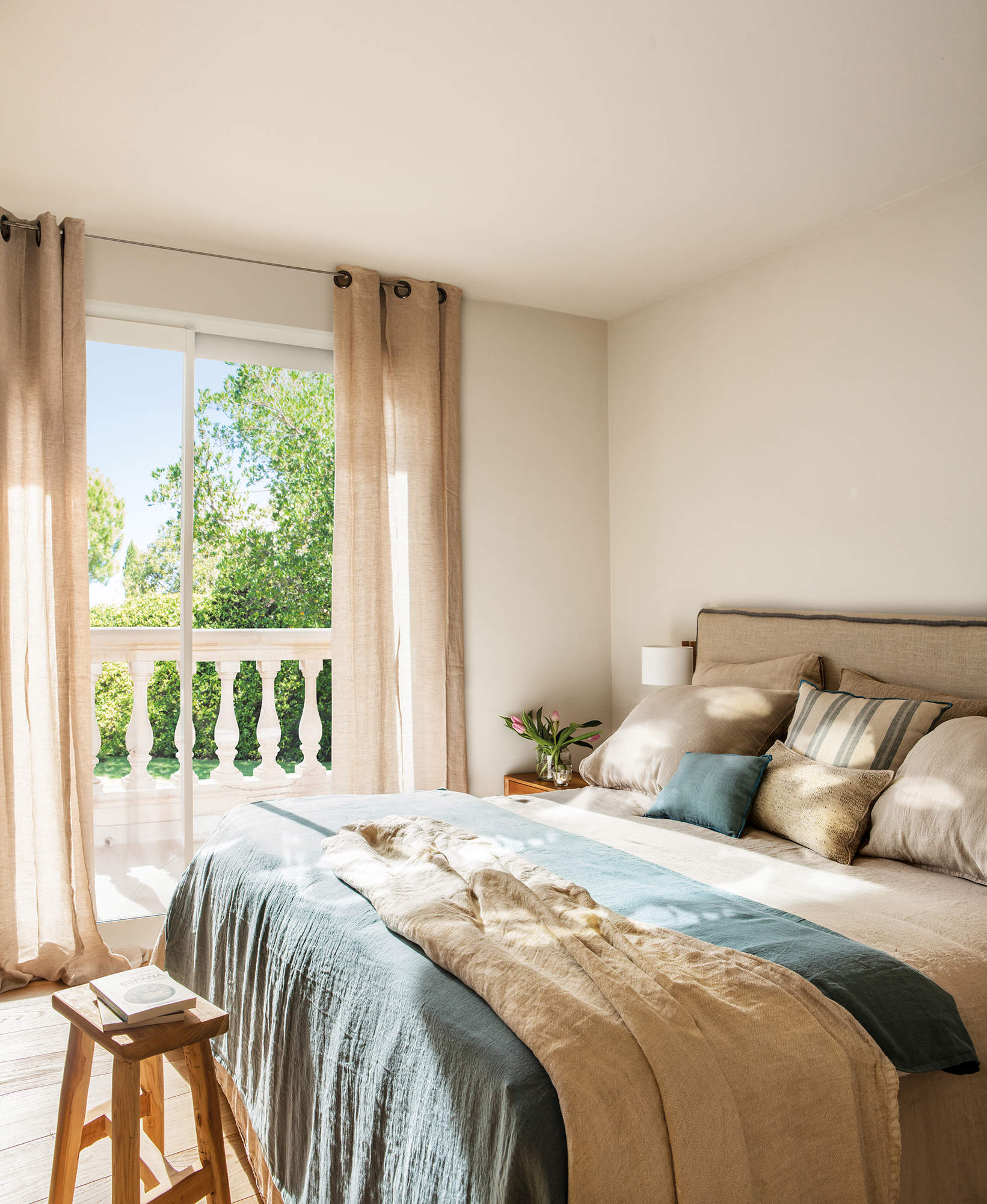 Dormitorio pequeño con textiles en tonos neutros y cortinas que caen desde el techo