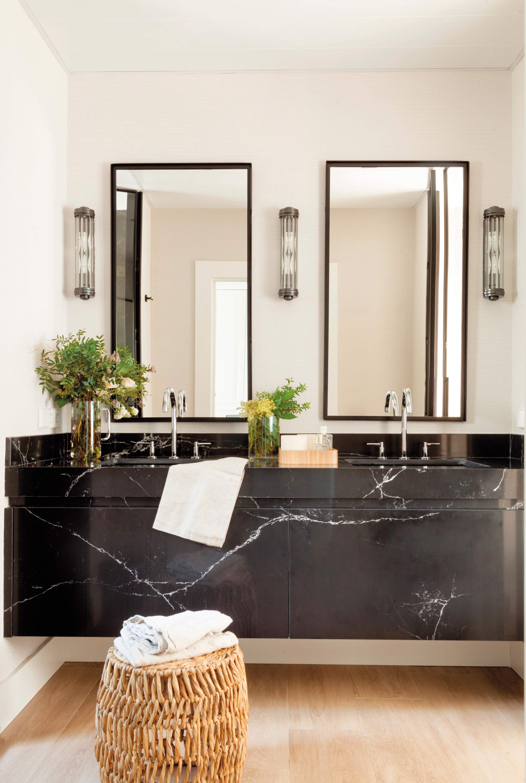 Baño con mueble de mármol negro con espejos y apliques