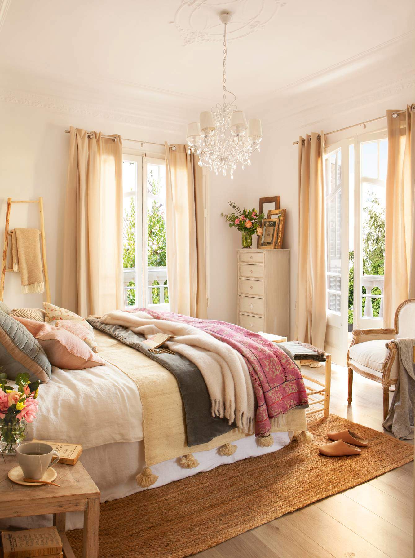 Dormitorio de base neutra y cama vestida con textiles superpuestos de distintos colores
