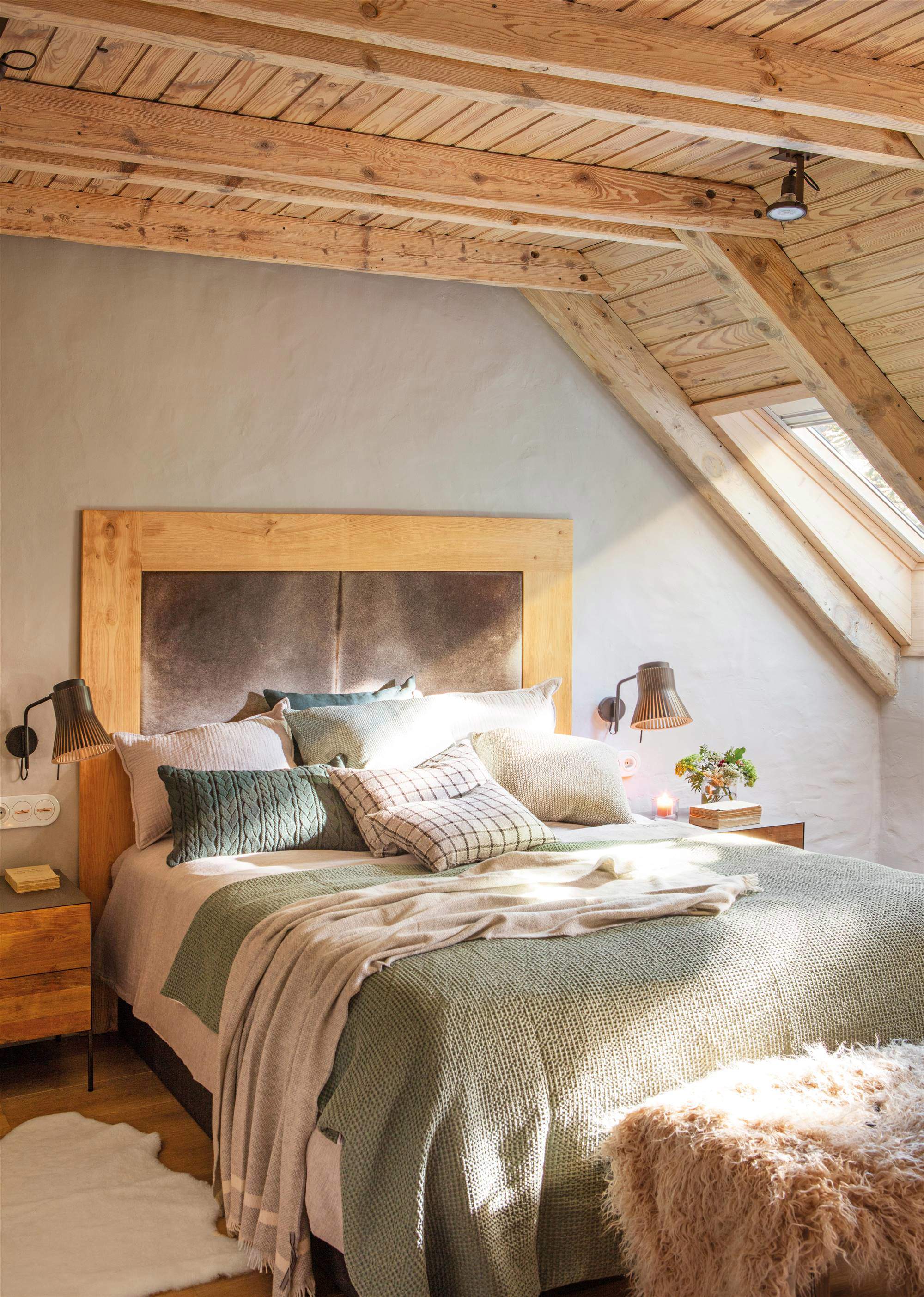 Dormitorio con techo de madera y gran cabecero de madera tapizado.