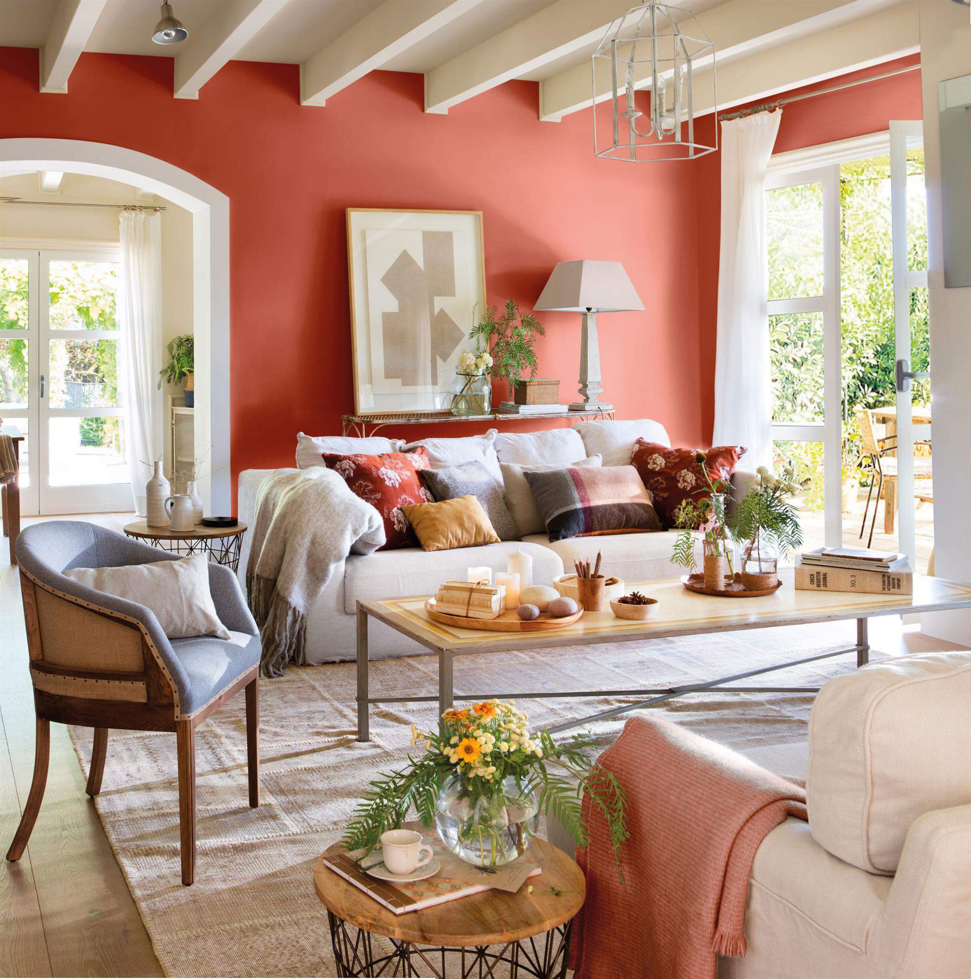 Salón con paredes pintadas en rojo y sofás blancos.