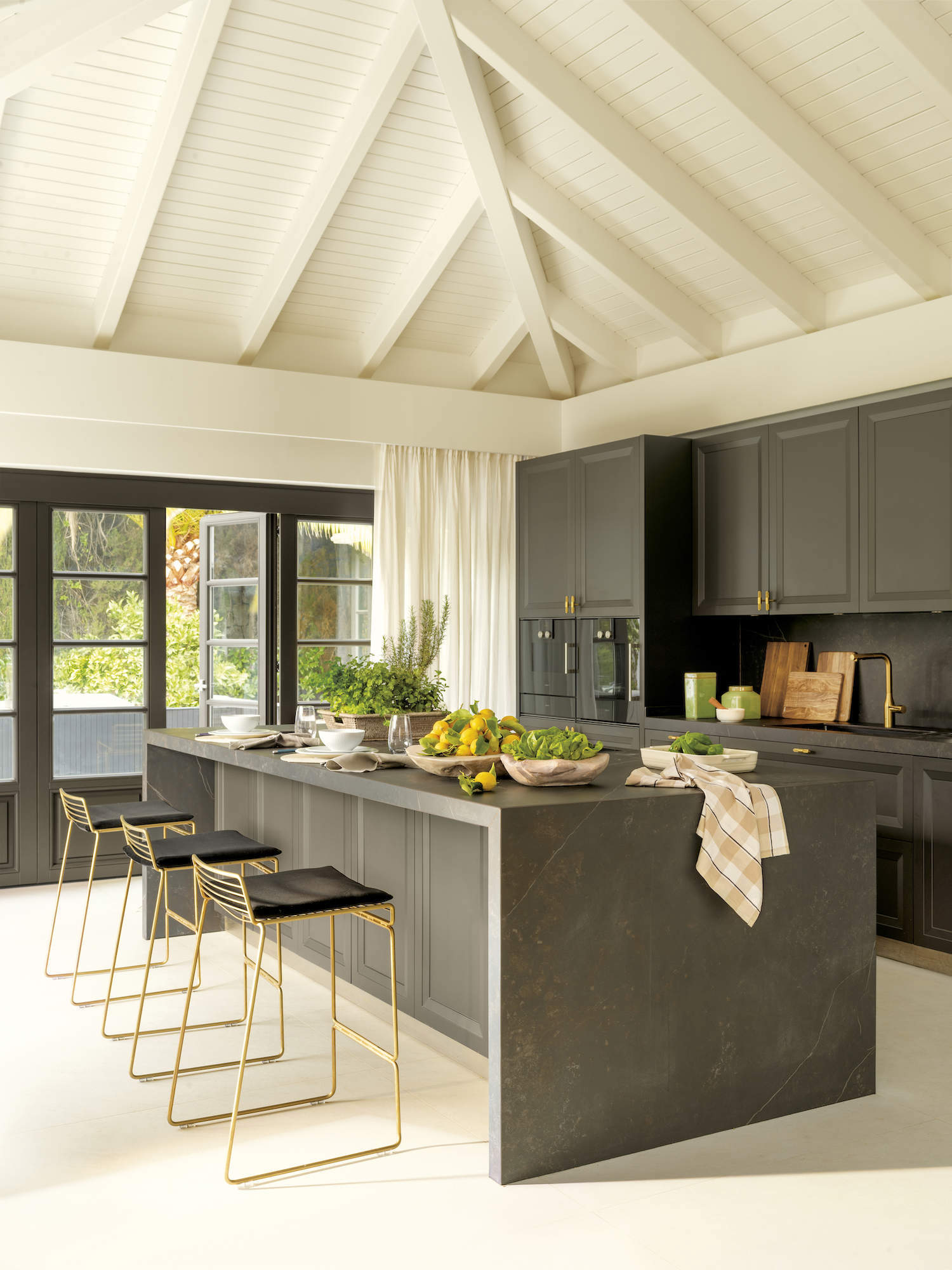 Cocina con isla central y mobiliario y electrodomésticos panelados en color negro