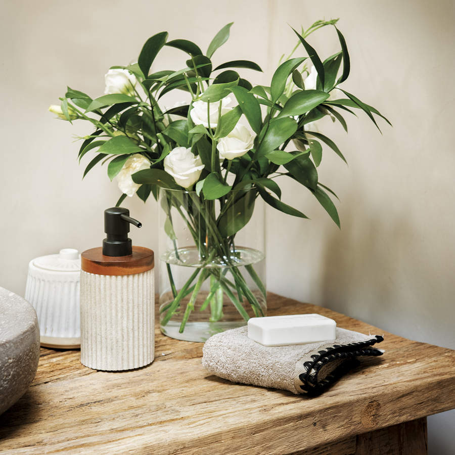 baño, mueble de madera con cajones, florero, flores blancas, jabón, dispensador de jabón
