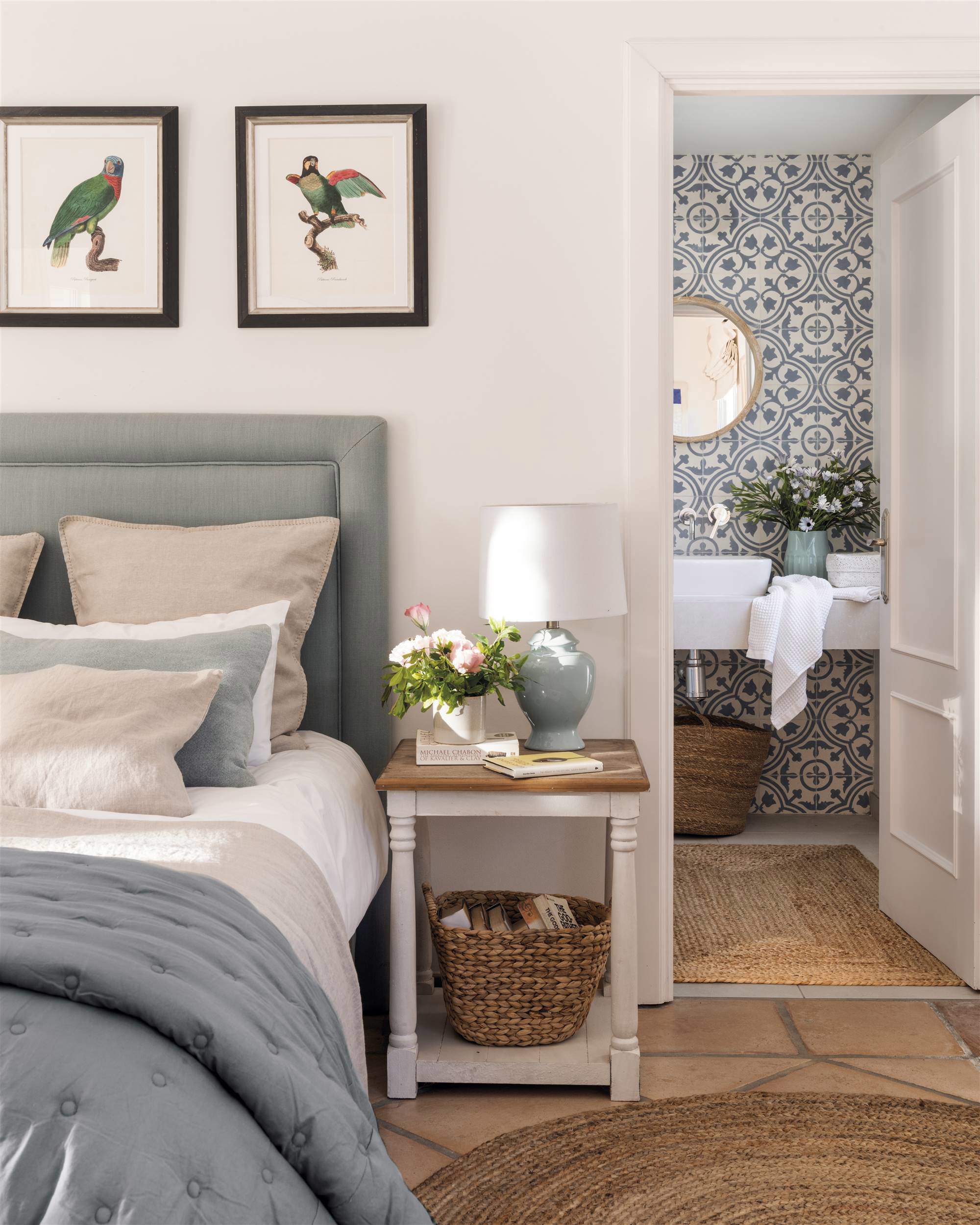 Dormitorio con cabecero tapizado y cuadros de pájaros.
