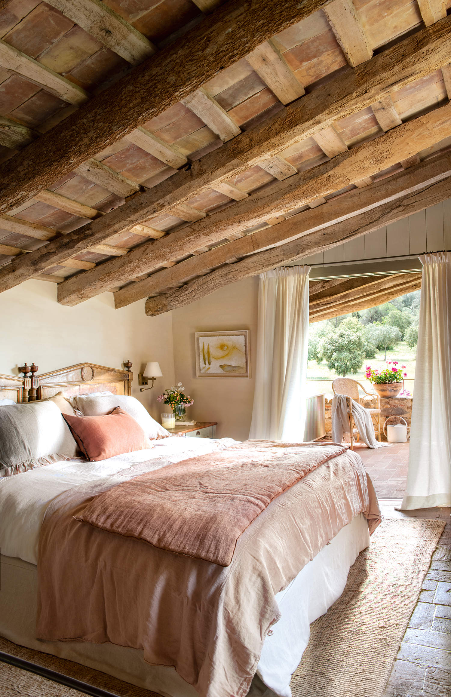 Dormitorio rústico con terraza, con vigas de madera, suelos de barro, alfombra de yute