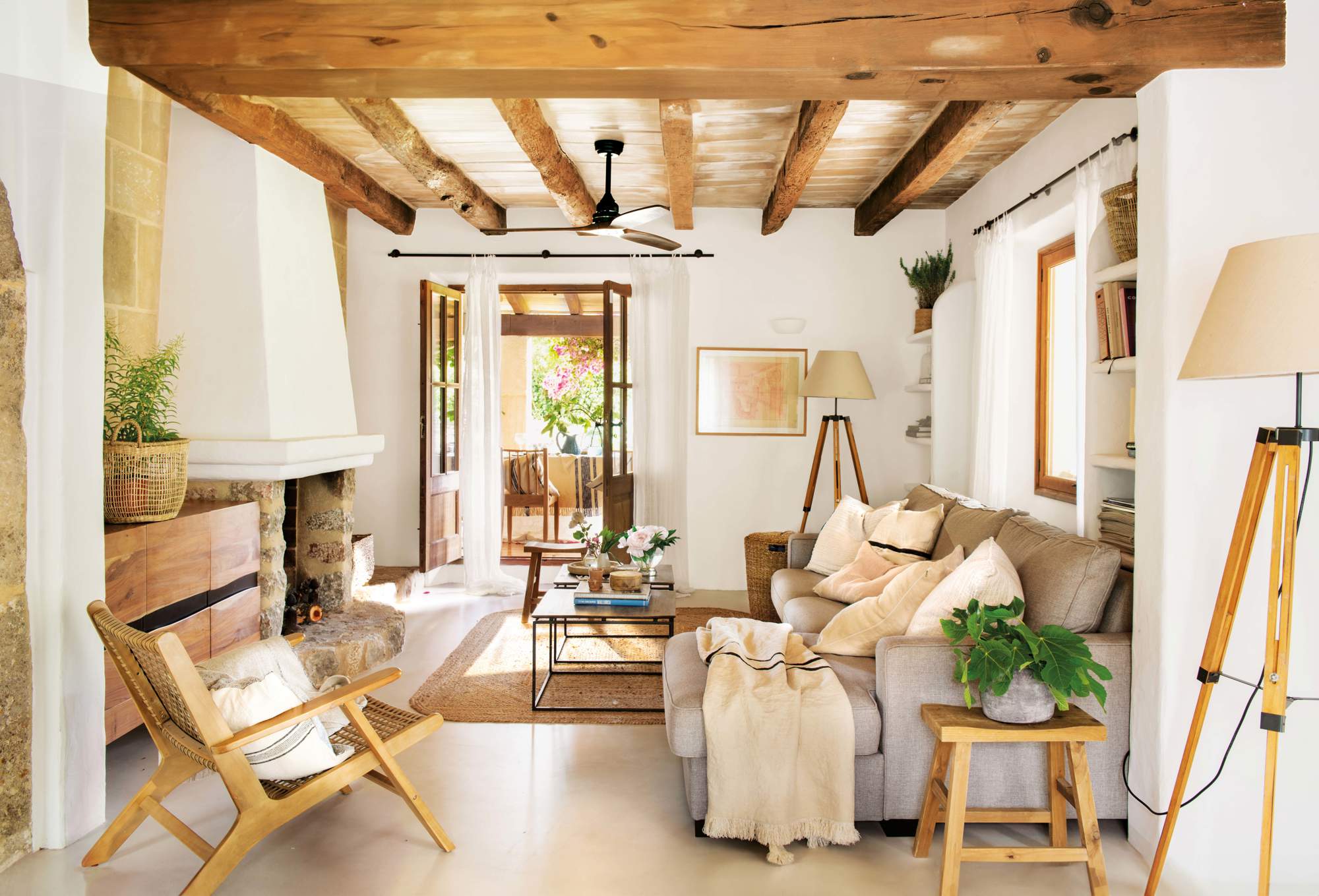 Salón pequeño con vigas de madera en el techo, chimenea, sofá con chaise longue, butaca y lámparas de pie