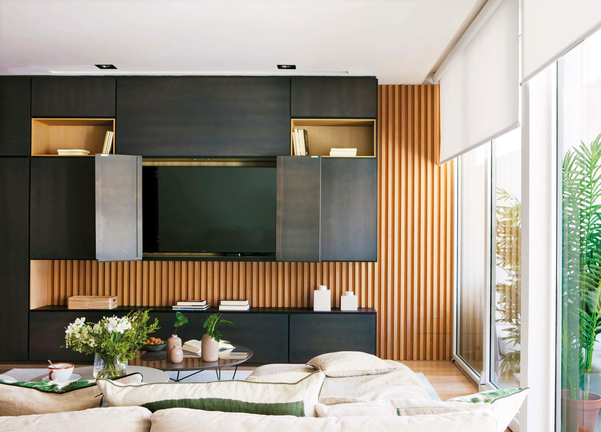 Salón con mueble lacado en negro y con trasera de madera que oculta la televisión