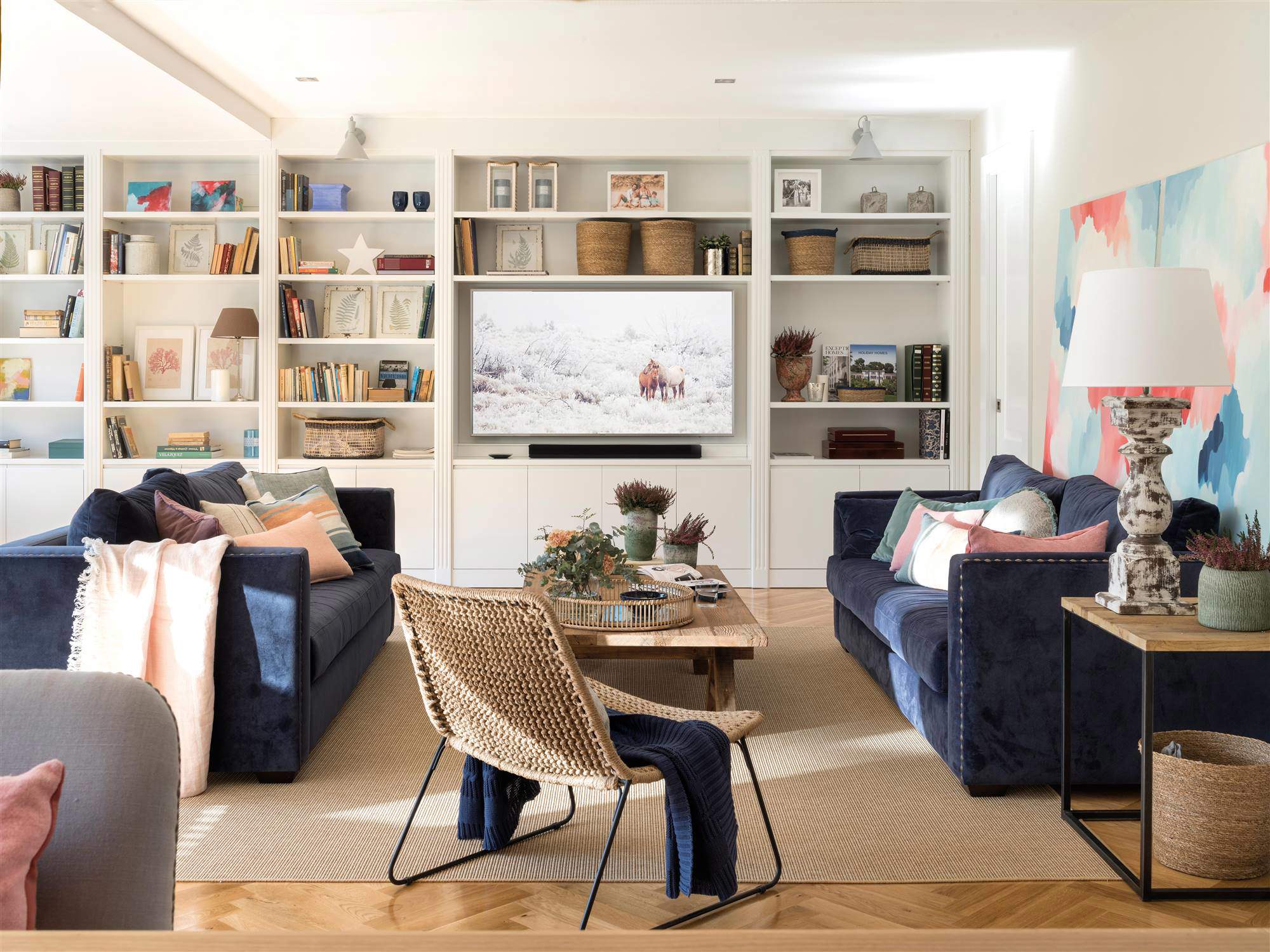 Salón con sofás enfrentados de terciopelo azul y amplia librería de lado a lado.