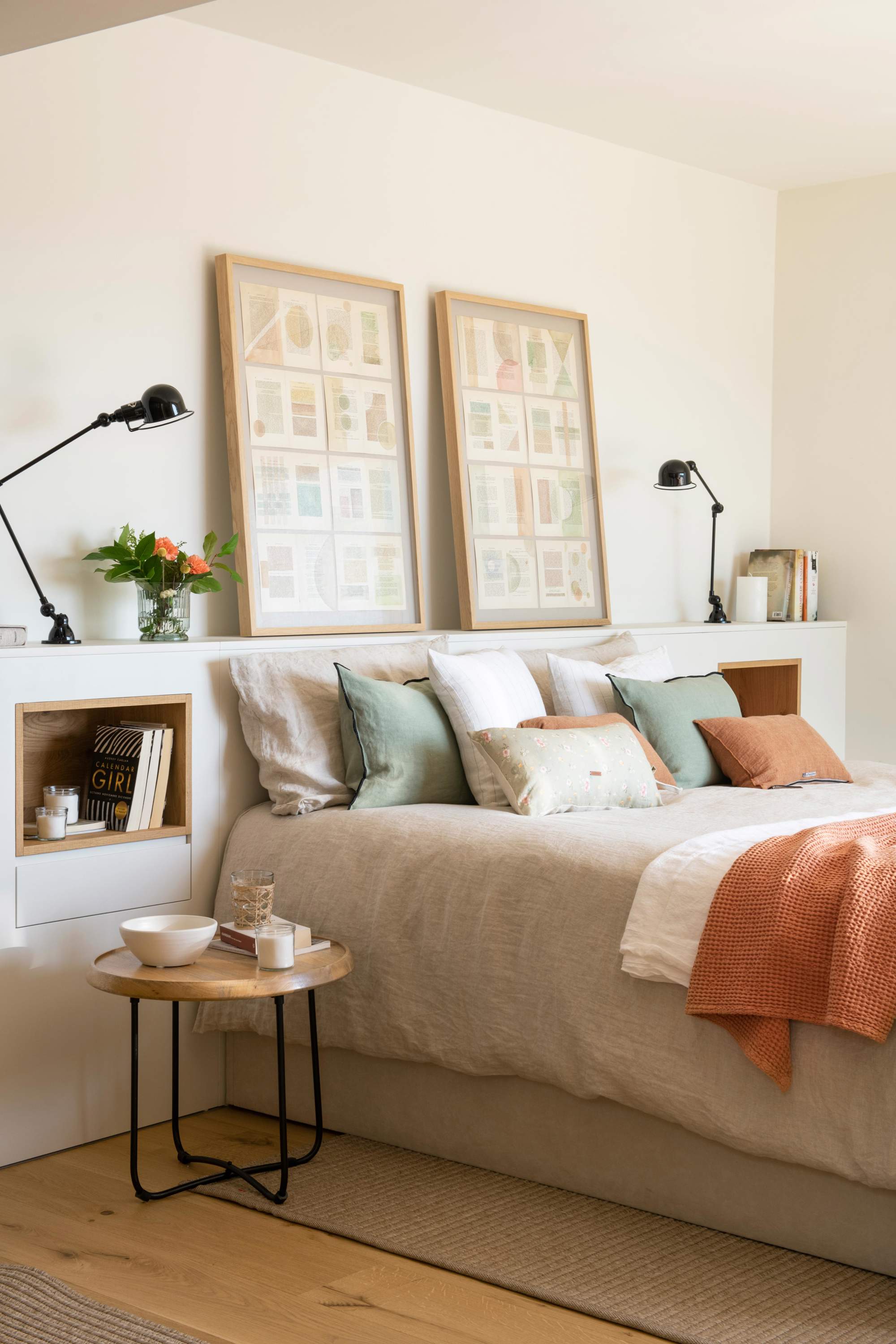 Dormitorio con cabecero de obra, mesillas redondas plegables, flexos y cuadros
