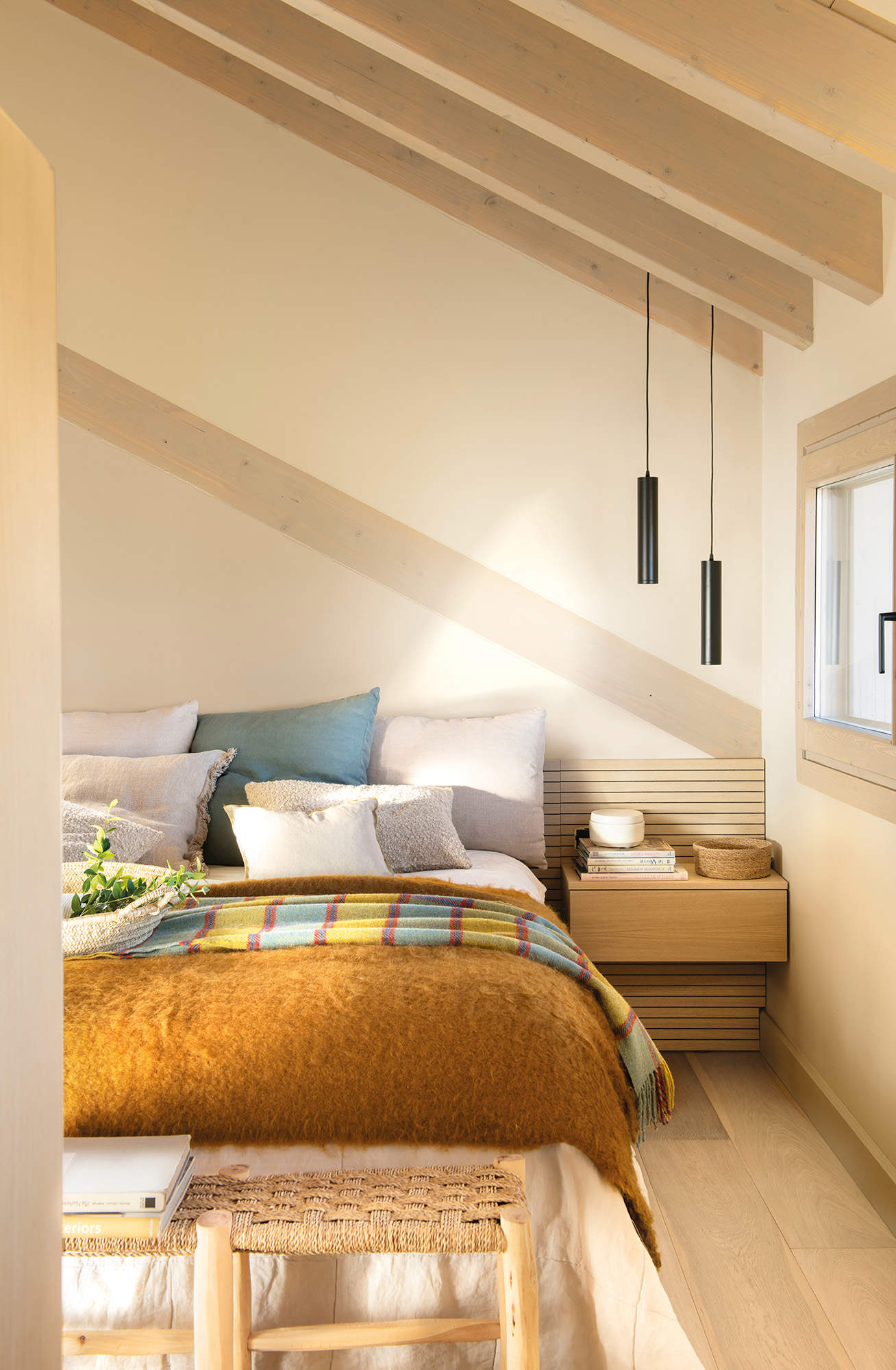 Dormitorio pequeño y abuhardillado con cabecero alistonado, mesillas voladas y lámparas suspendidas tubulares