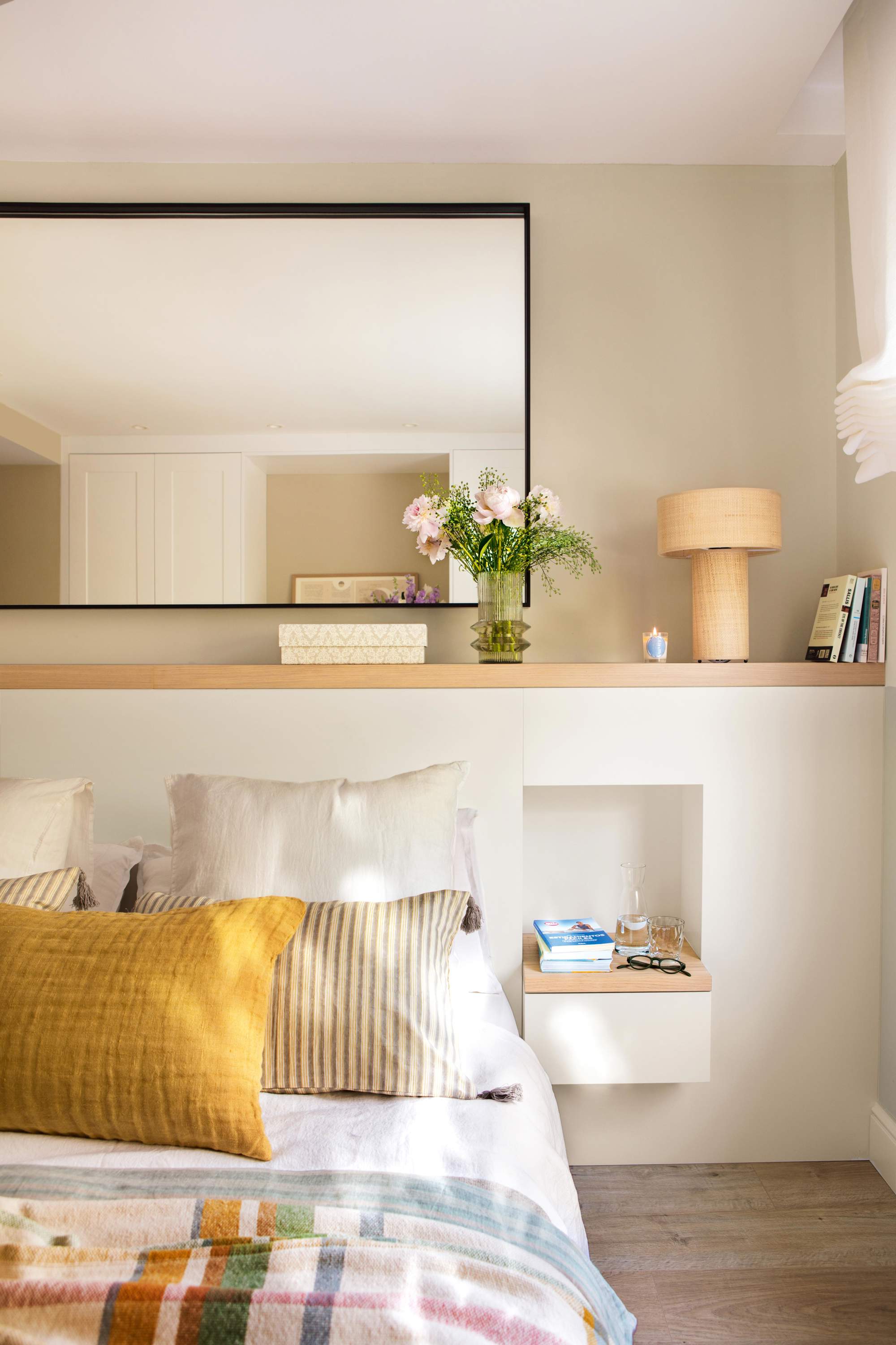 Dormitorio pequeño con cabecero de obra con mesillas integradas, espejo y lámpara sobremesa