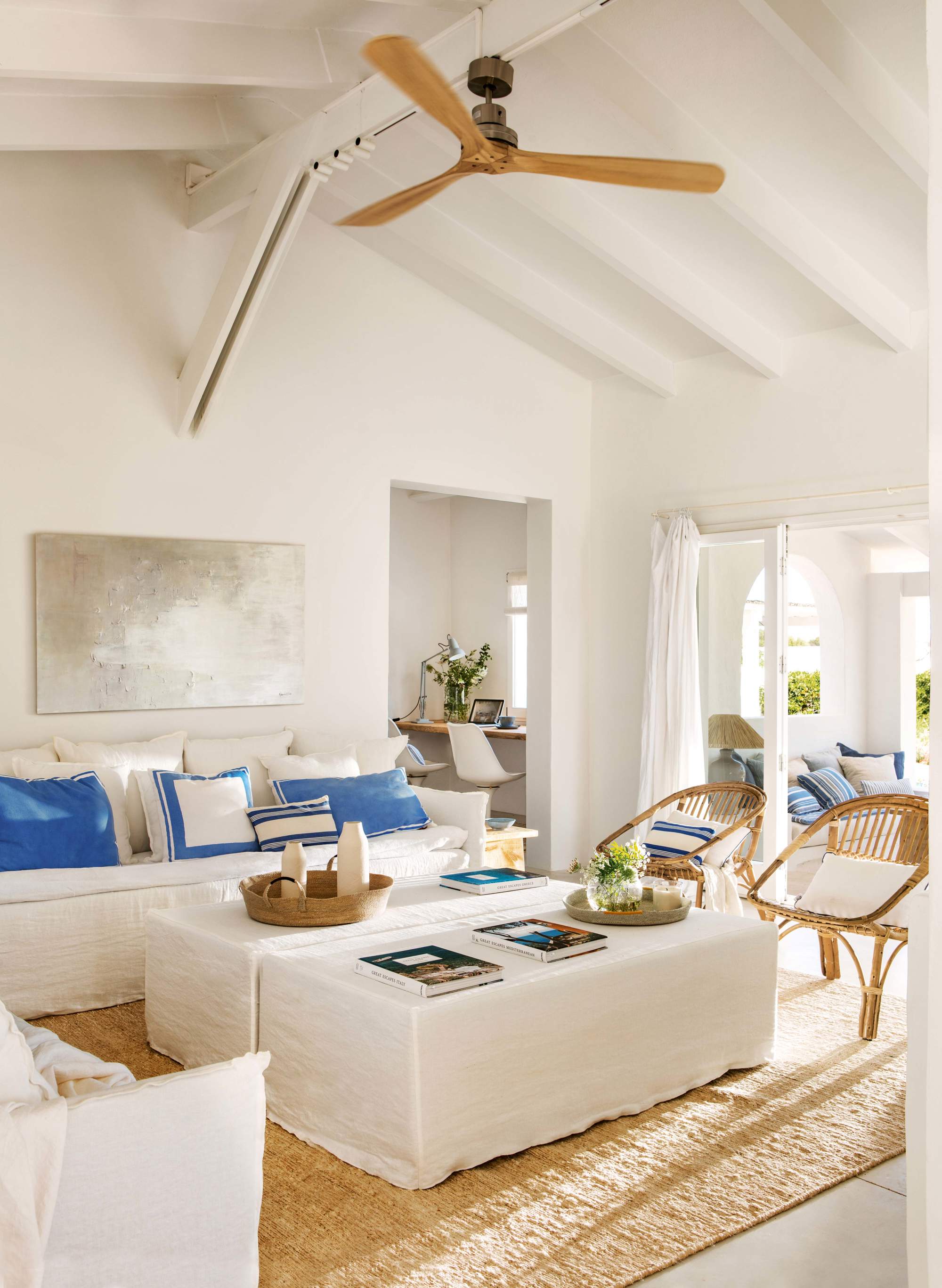 Salón blanco con cojines azules, alfombra de fibra y ventilador