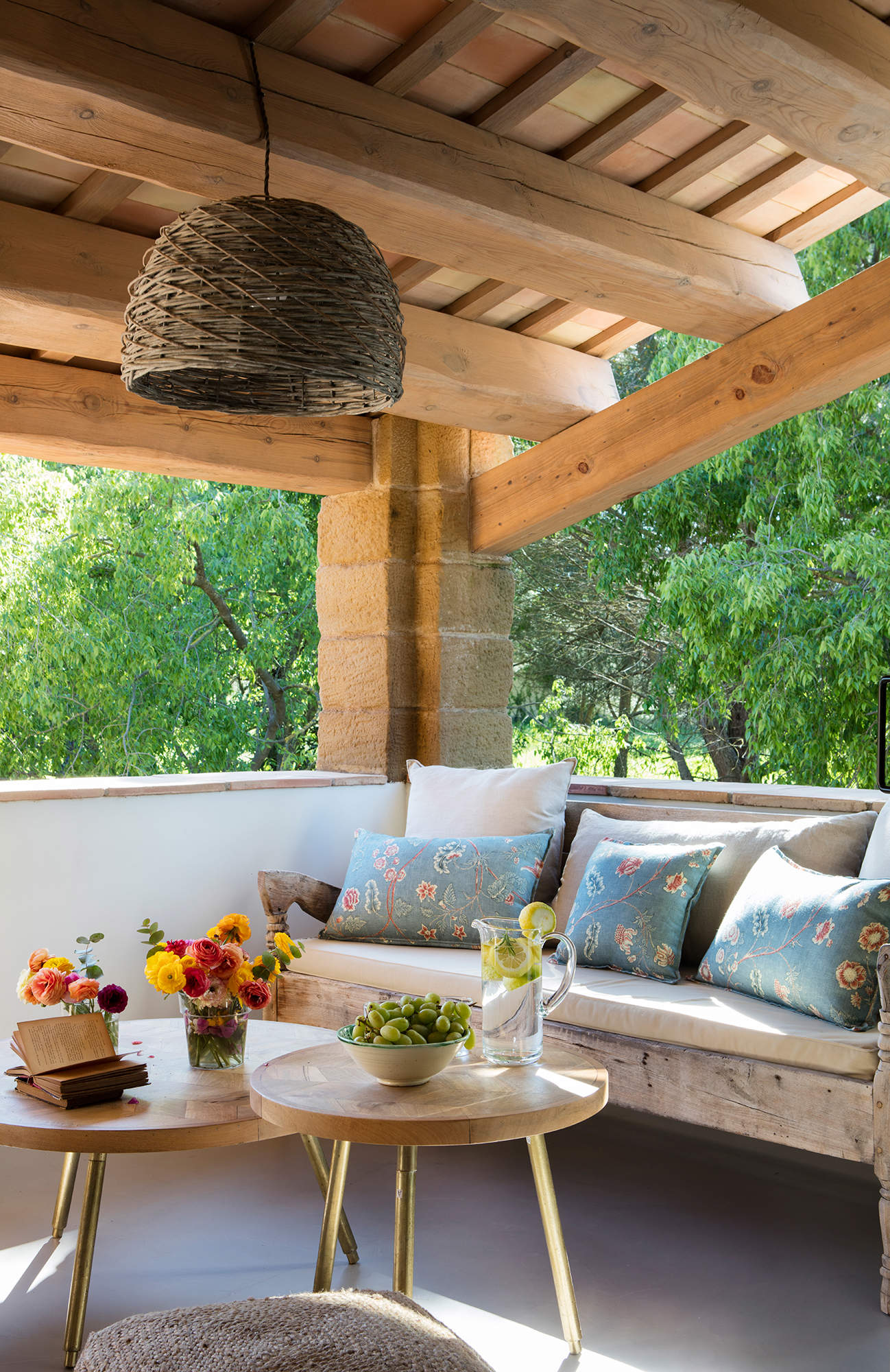 Terraza con mesas nido, sofá de madera y lámpara de fibra.