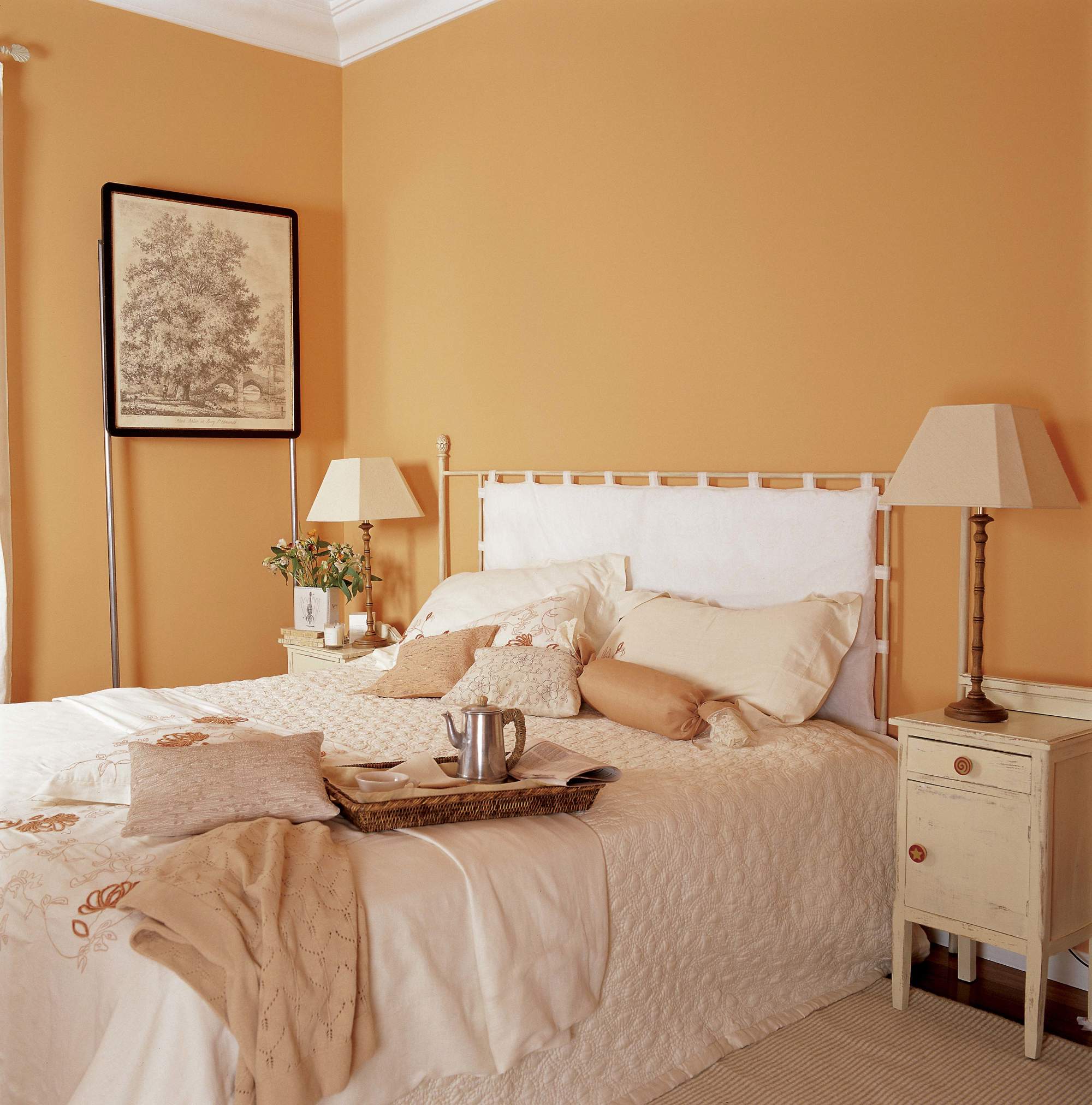Dormitorio con paredes pintadas de naranja, cabecero blanco y mesillas de noche 