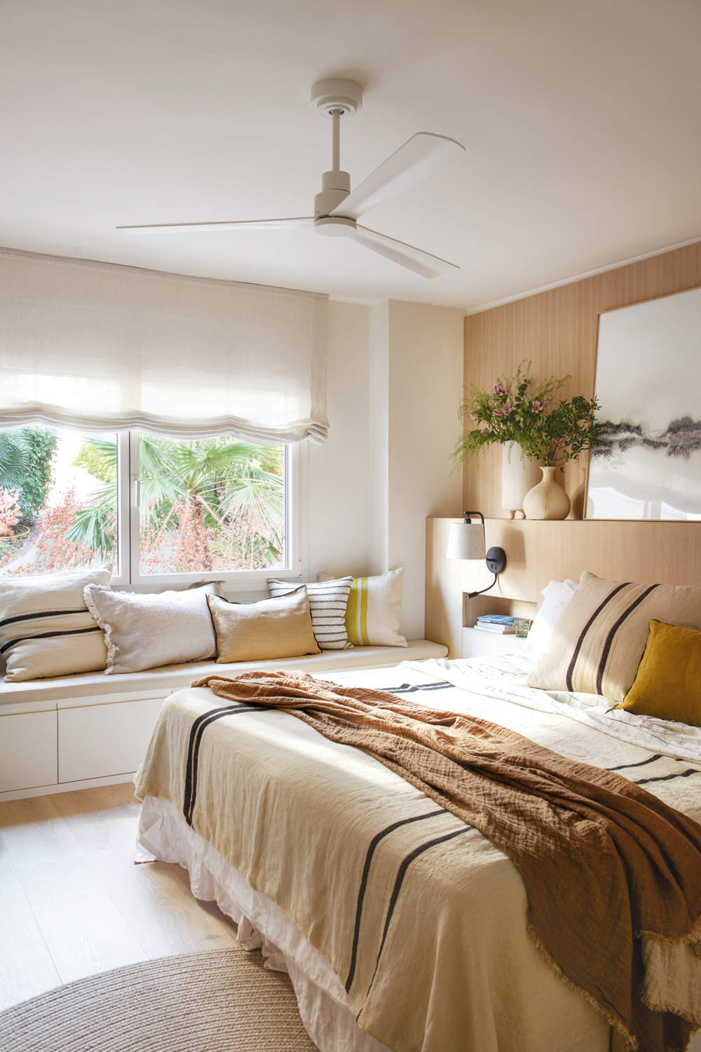 Dormitorio cálido con ropa de cama beige y mostaza y con banco bajo la ventana