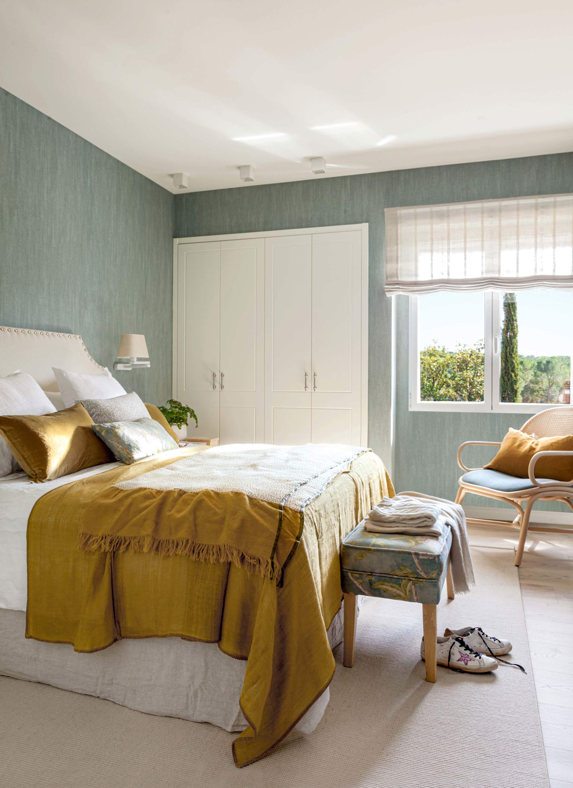 Dormitorio con papel pintado verde, armario empotrado y cabecero tapizado