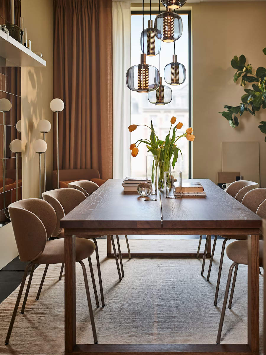 Comedor estrecho y moderno con pared de espejos, mesa de madera y sillas modernas