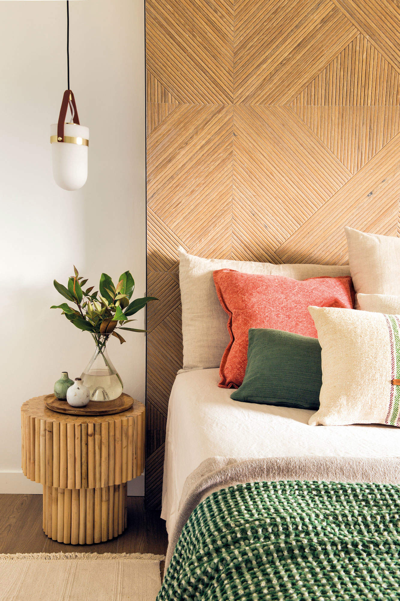 Dormitorio con cabecero porcelánico y taburete de madera a modo de mesilla.