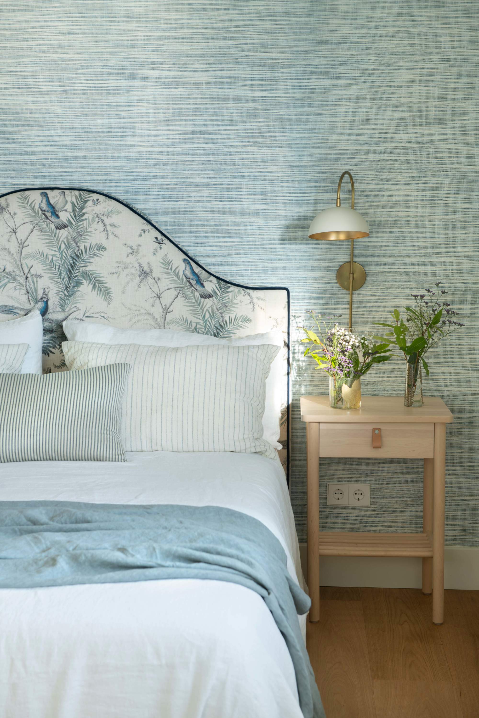 Dormitorio con cabecero tapizado y mesilla de noche de madera con cajón