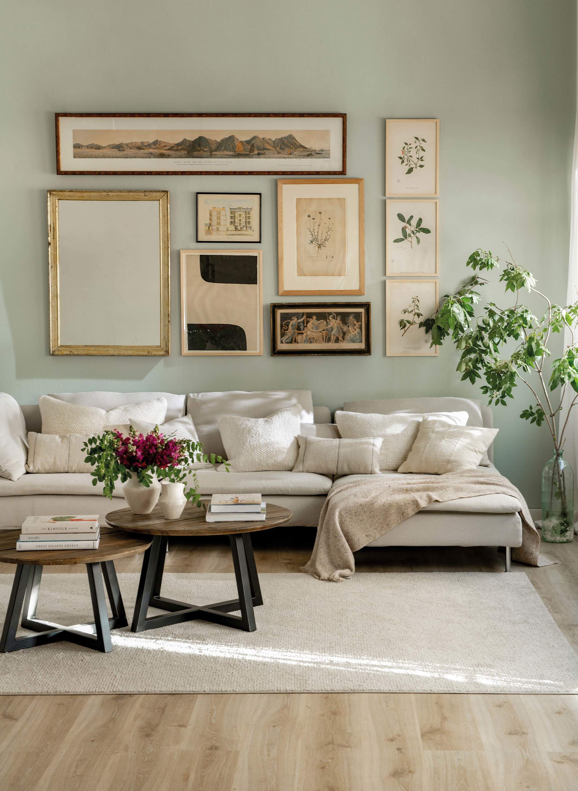 Salón con sofá con chaiselongue y composición de cuadros en la pared