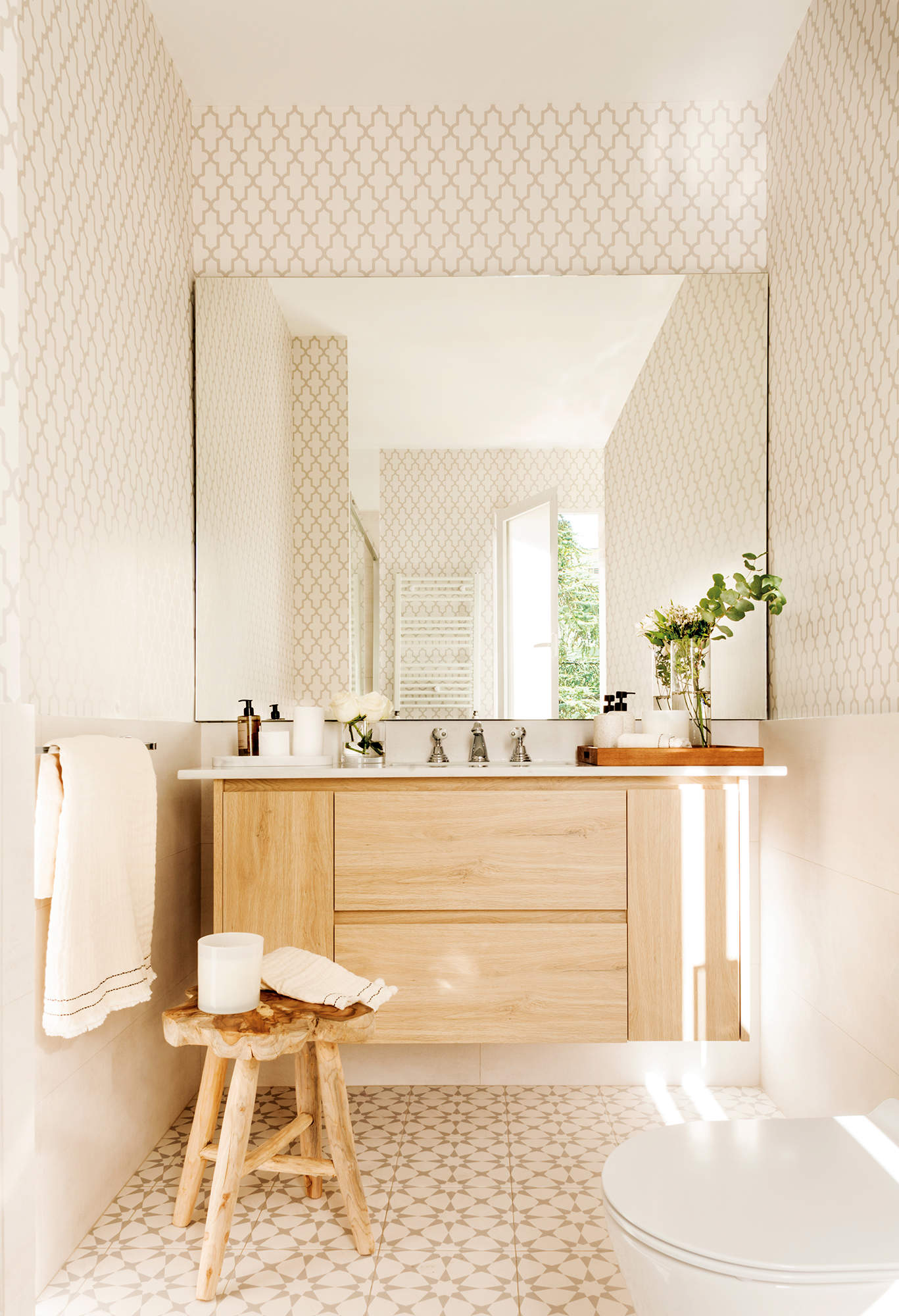 Baño con suelo hidraúlico, papel pintado, mueble volado y espejo de pared a pared
