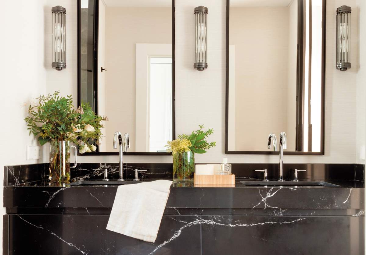 Baño con mueble de mármol negro con espejos y apliques