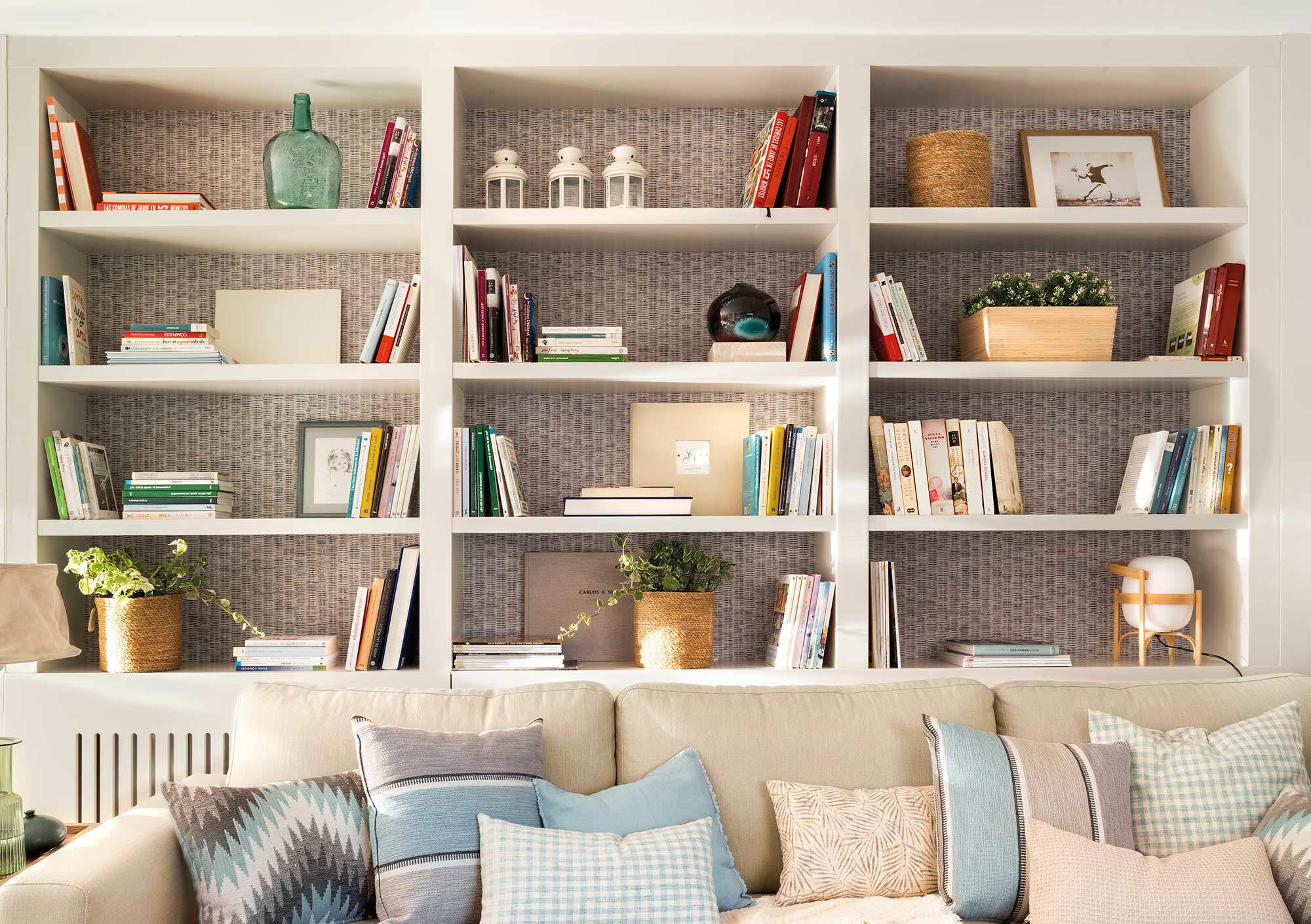 Salón con sofá y librería a medida con trasera de papel pintado